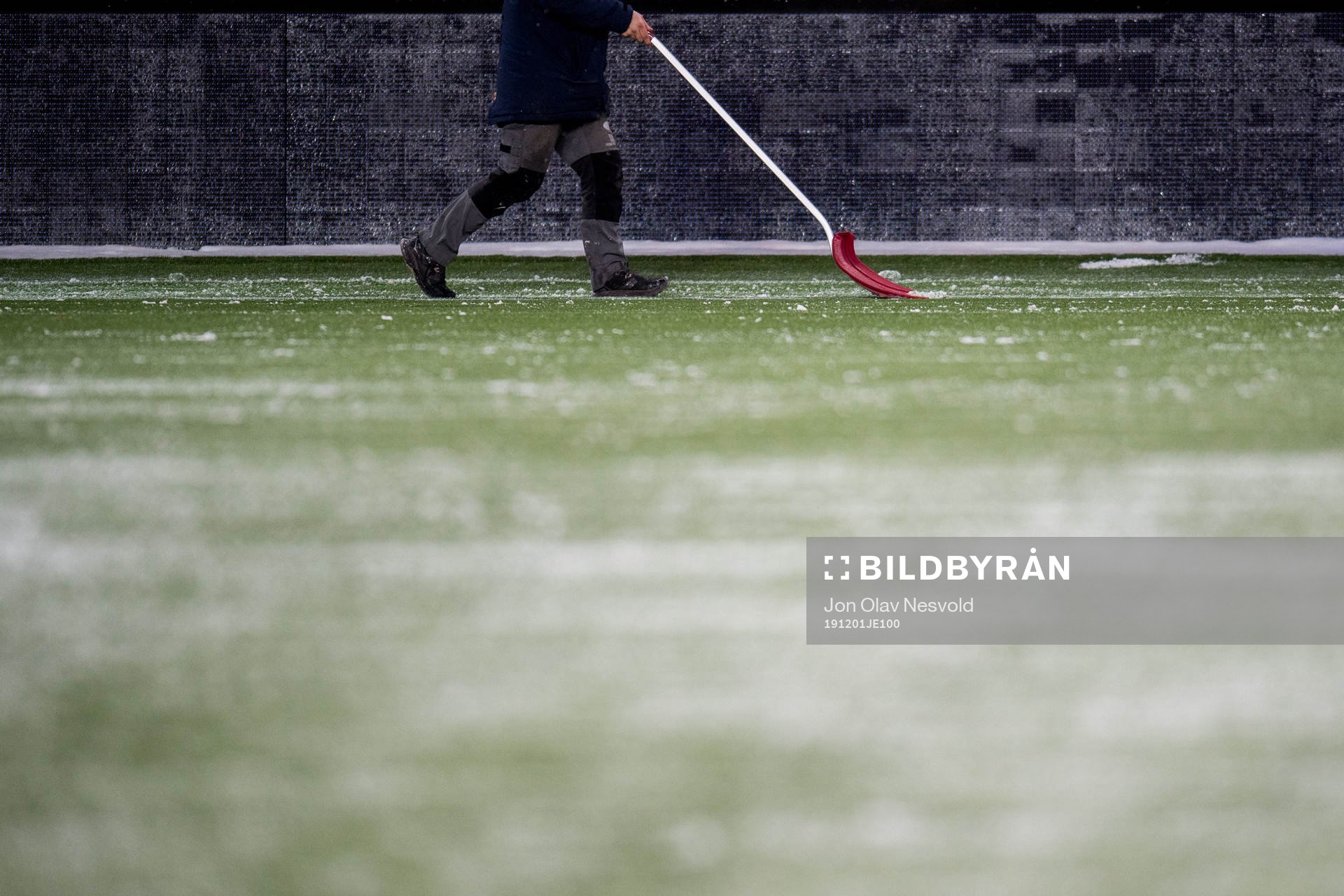 A man shuffles snow from the pitch
