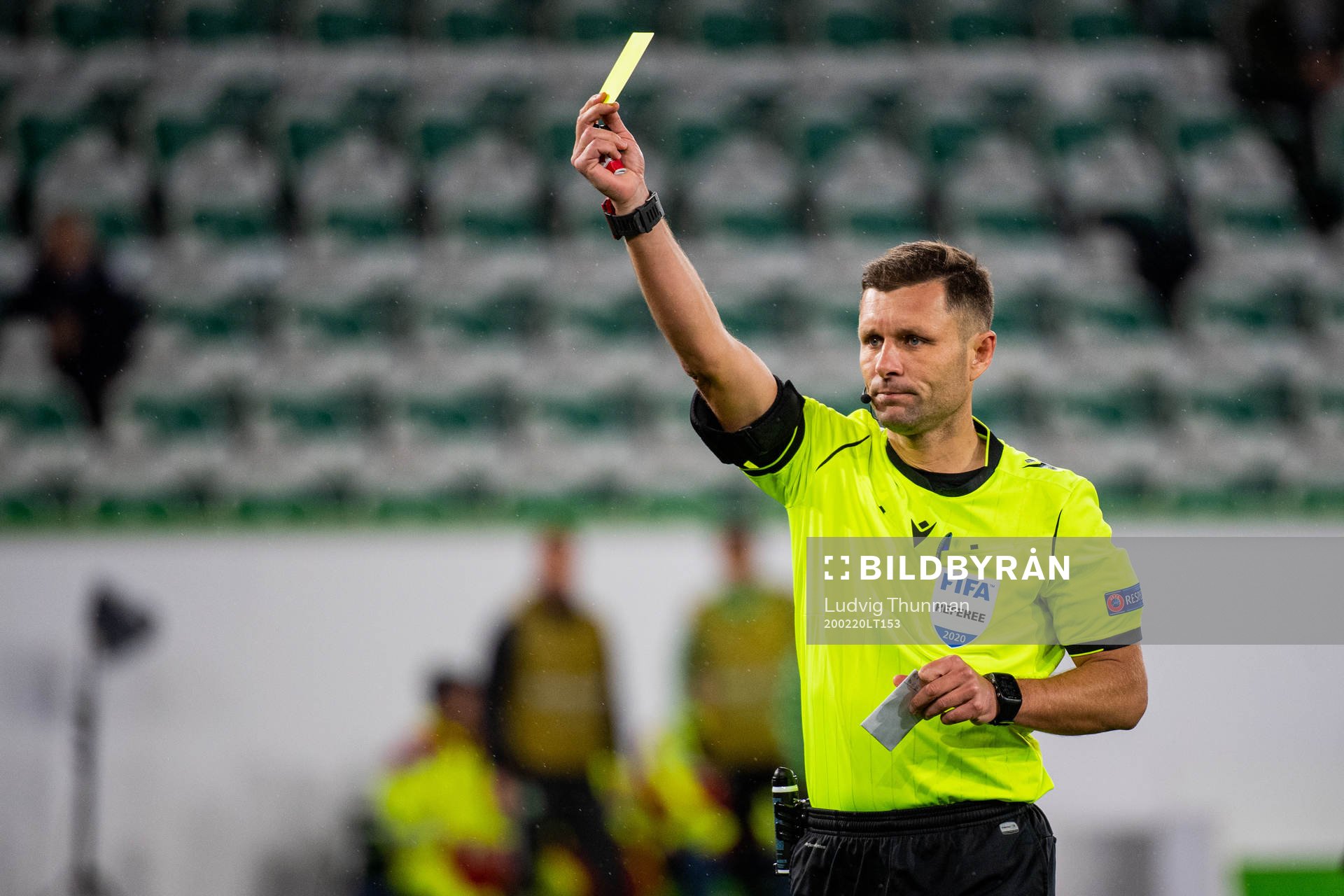 Referee Gediminas Mažeika gives a yellow card
