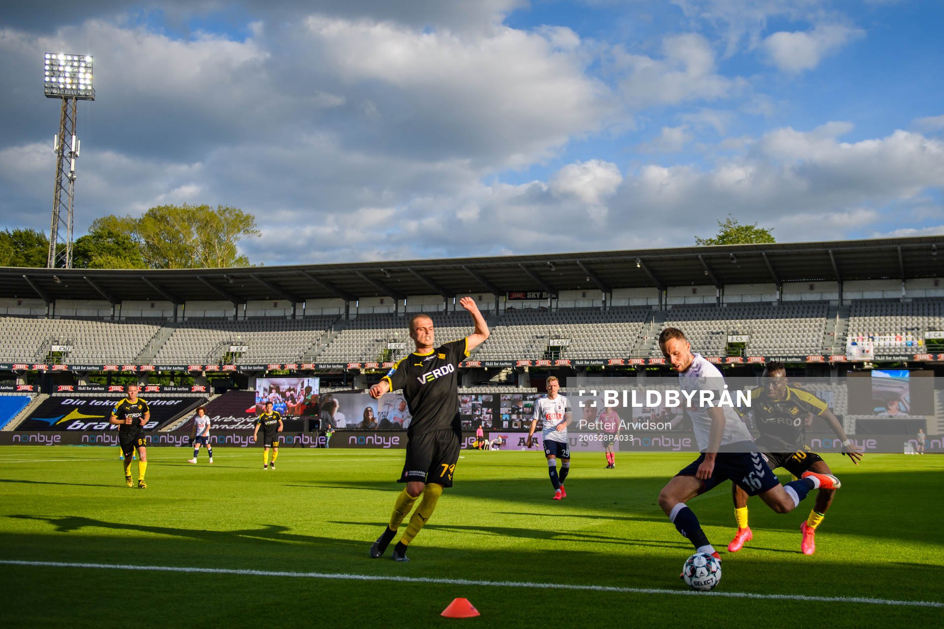 Mikkel Kallesö and Alhaji Kamara of Randers in action with Casper Höjer Nielsen of Aarhus infront of a virtual grandstand with supporters during the Danish Superliga match between AGF Aarhus and Randers FC which are played without spectators due to the coronavirus covid-19, on May 28, 2020 in Aarhus.