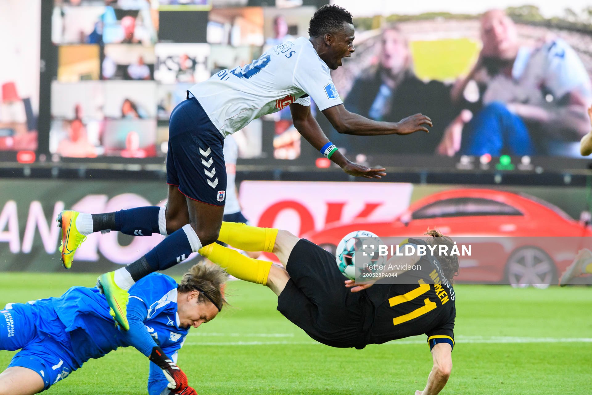 Mustapha Bundu of Aarhus in action with goalkeeper Patrik Carlgren and Erik Marxen of Randers infront of a virtual grandstand with supporters during the Danish Superliga match between AGF Aarhus and Randers FC which are played without spectators due to the coronavirus covid-19, on May 28, 2020 in Aarhus.