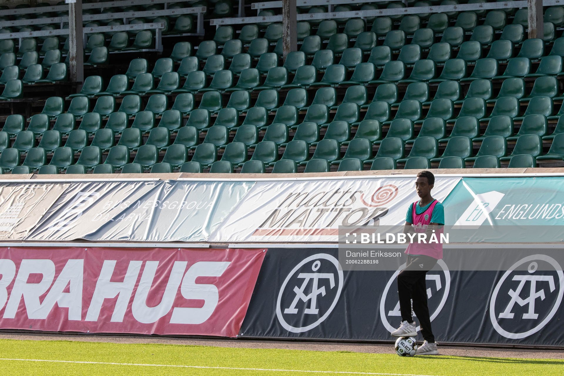 Bollkalle framför tomma läktare innan fotbollsmatchen i