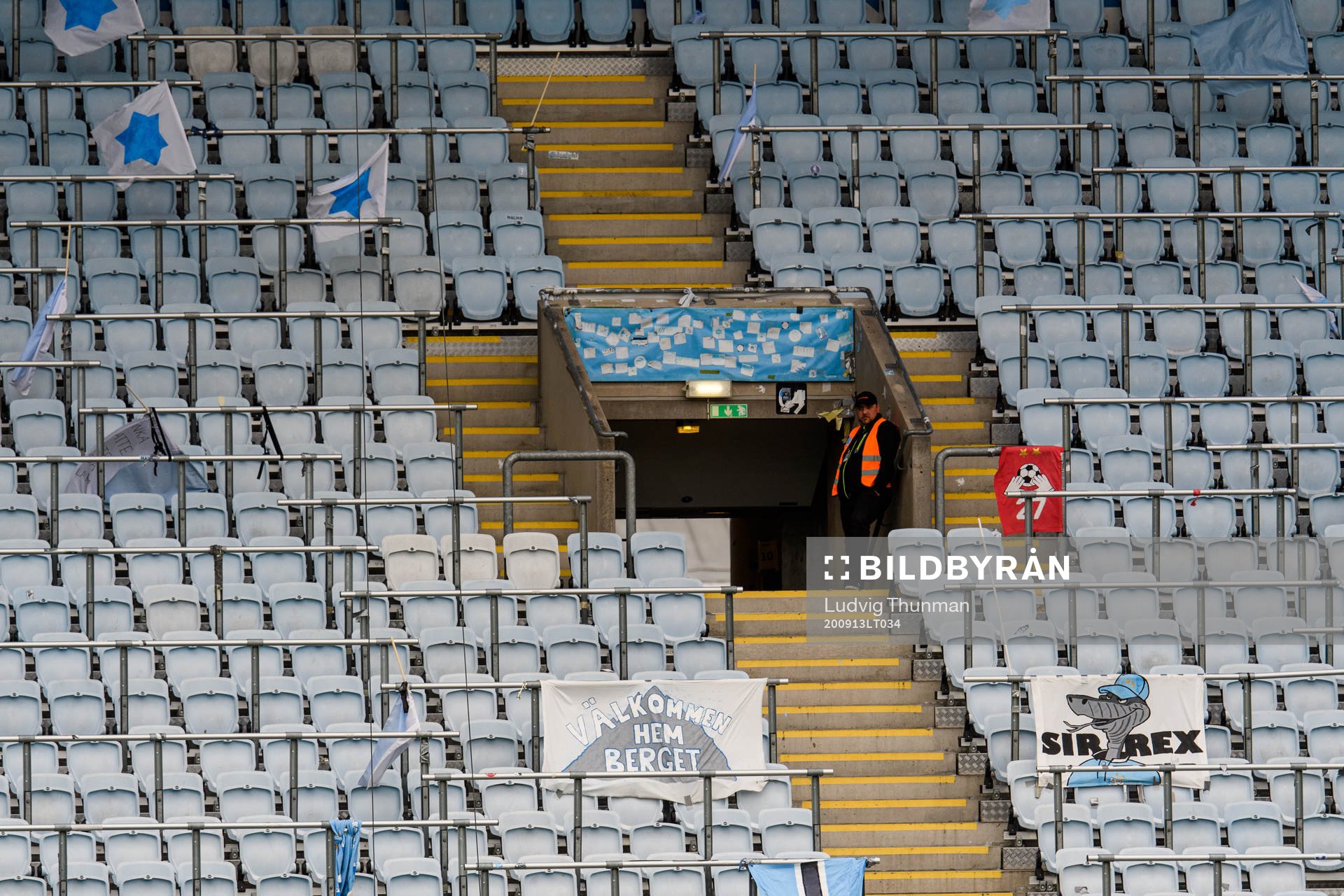 En ensam publikvärd på en tom läktare med flaggor under fotbollsmatchen i Allsvenskan mellan Malmö FF och AIK den 13 september 2020 i Malmö.