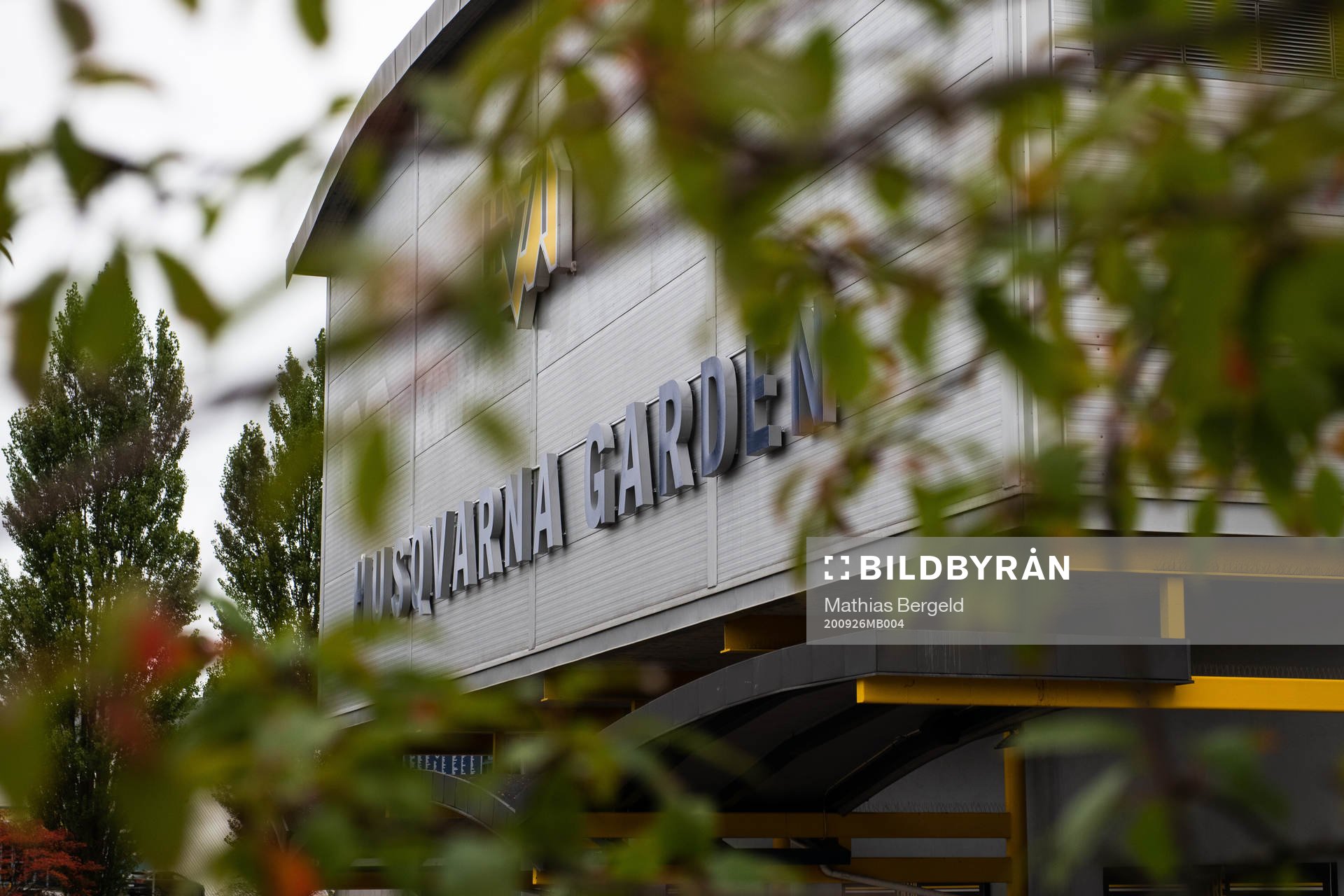 Skylt på Husqvarna Garden med träd i förgrunden