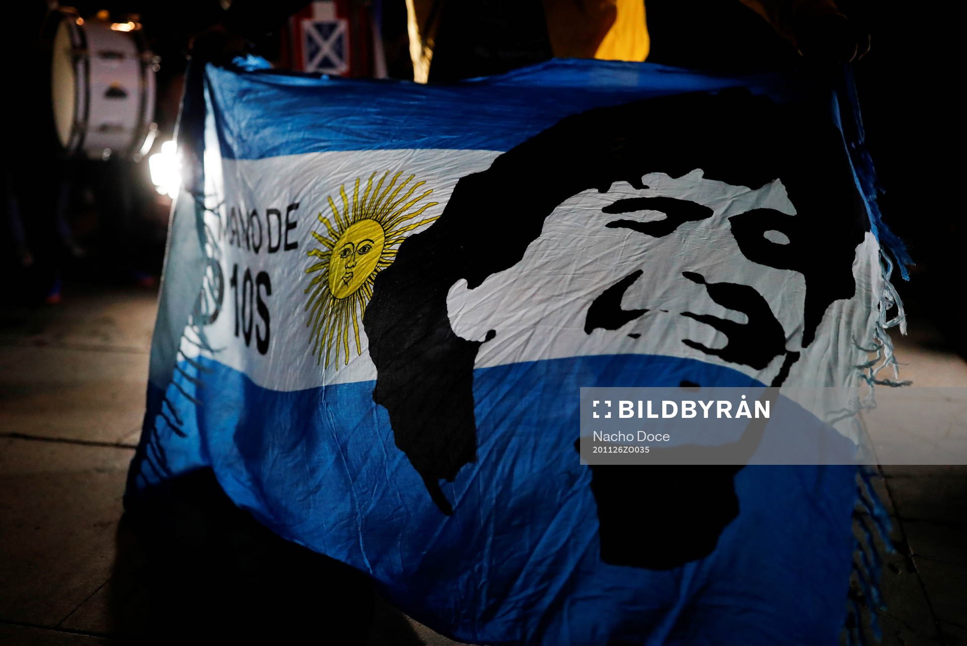 A soccer fan holds an Argentine flag with the face of late