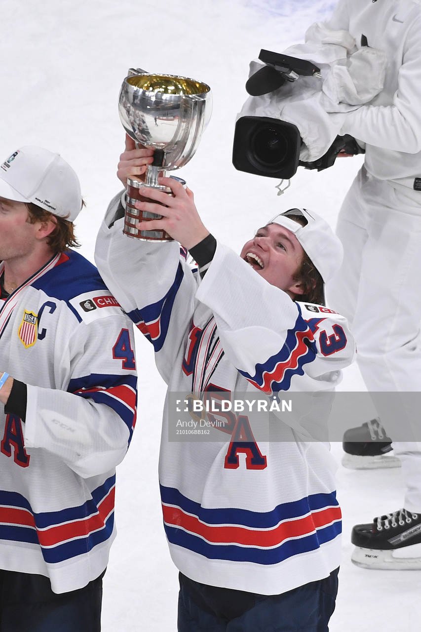 Cole Caufield of USA holds up the championship trophy