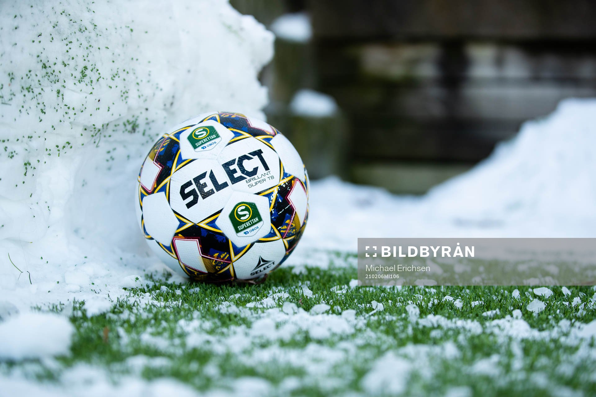 En fotboll vid en snövall bredvid planen