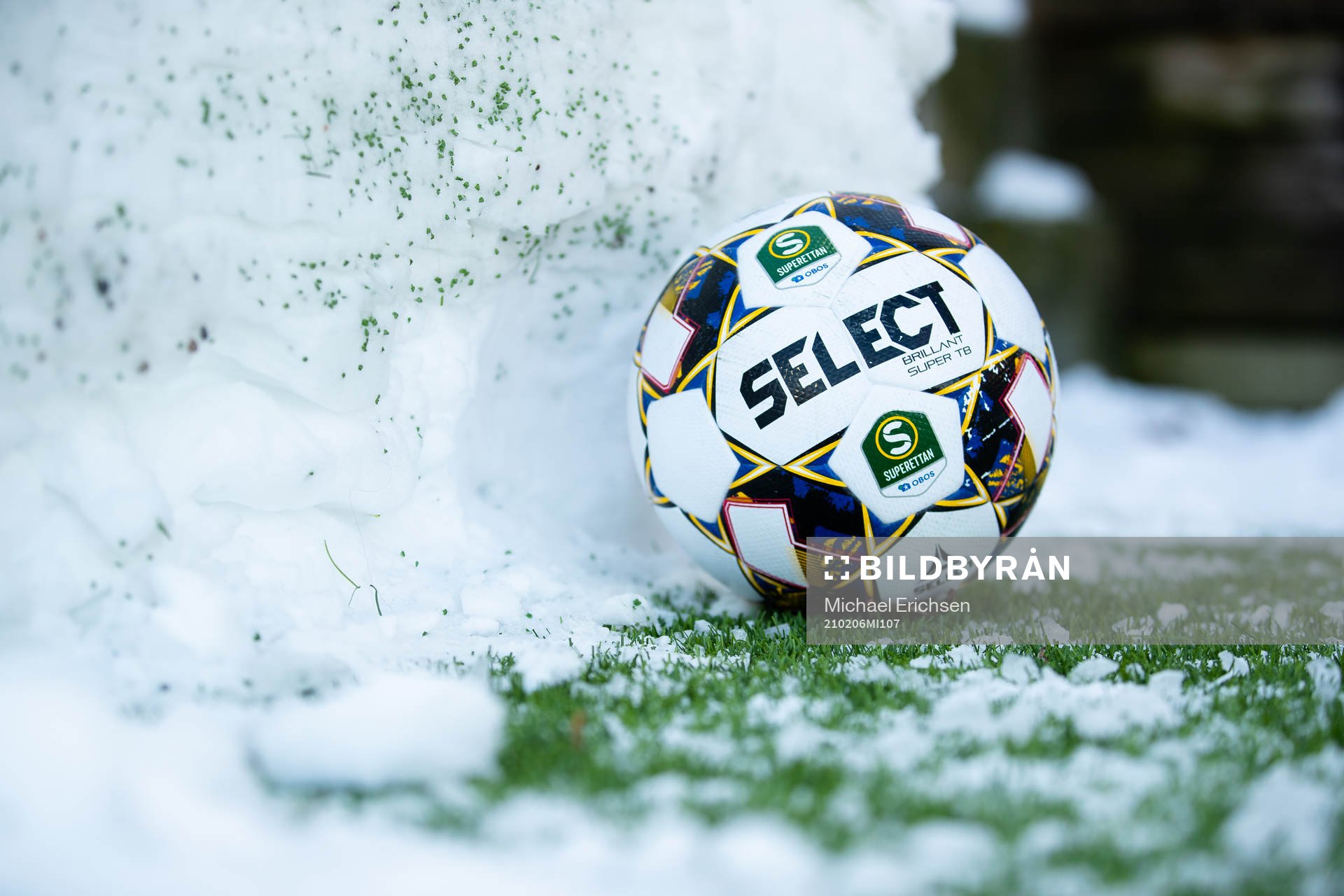 En fotboll vid en snövall bredvid planen