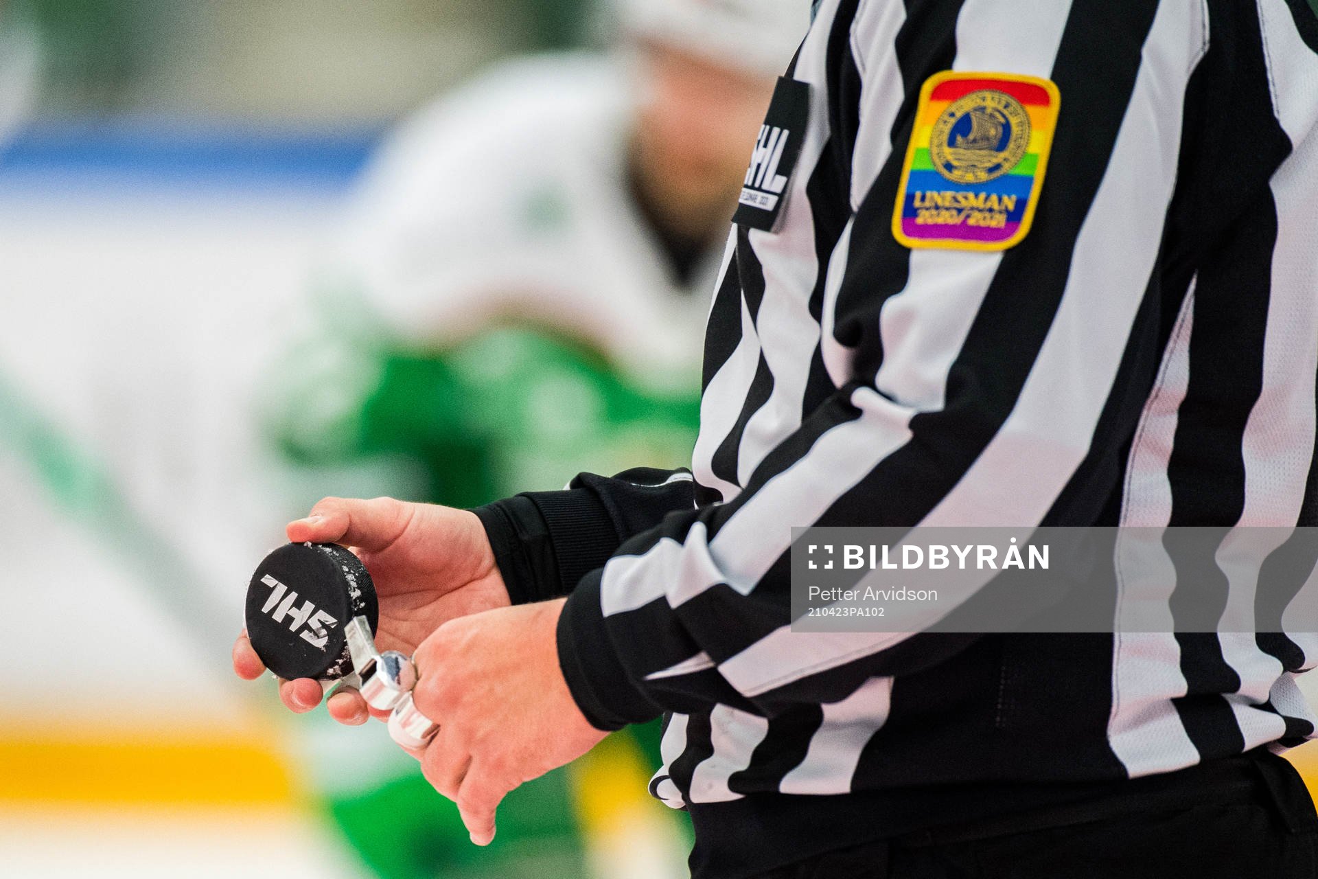En domare håller i sin visselpipa och en matchpuck