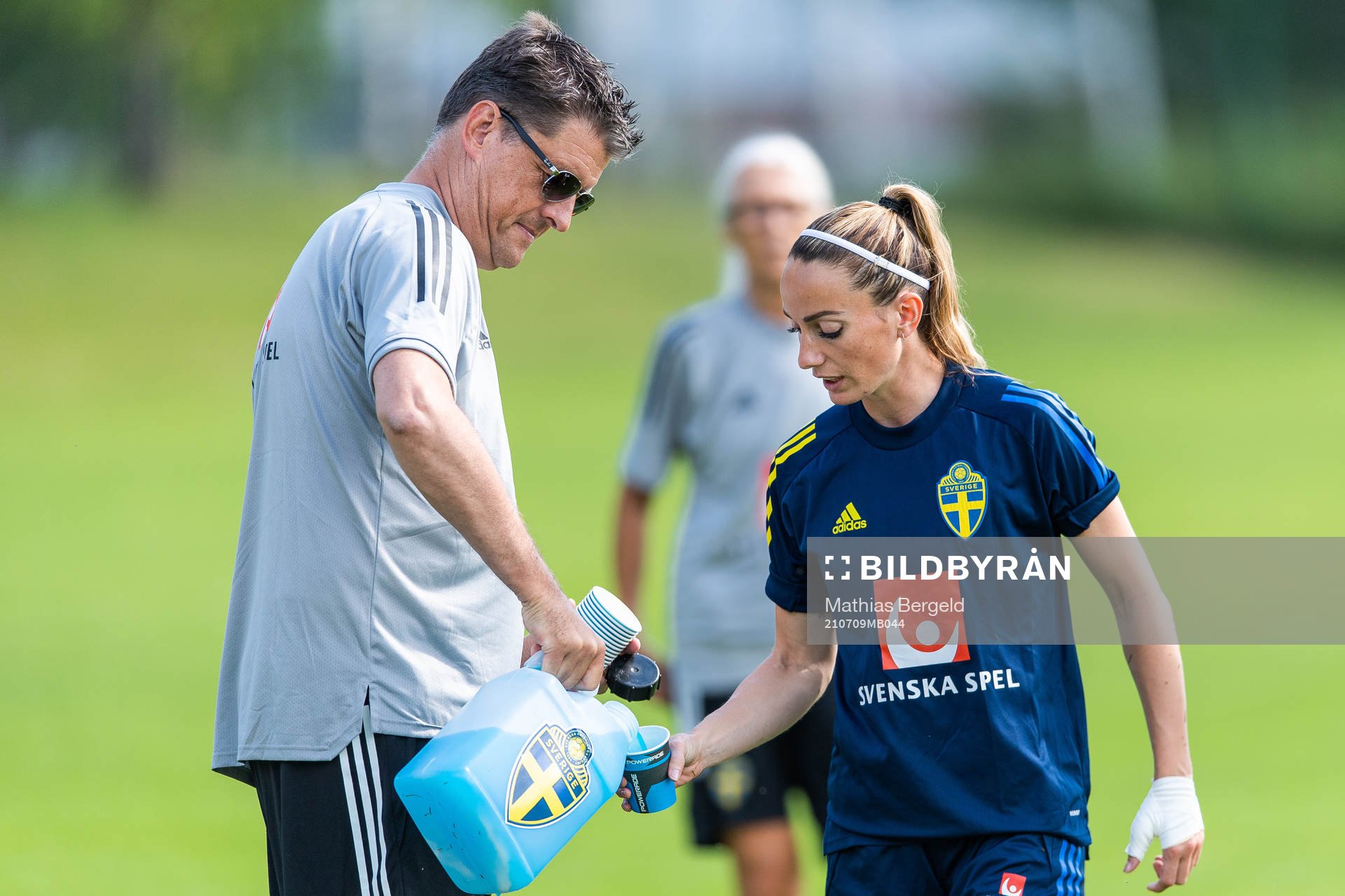 Läkare Mats Börjesson häller upp dricka till Kosovare Asllani under en träning med Sveriges damlandslag i fotboll den 9 juli 2021 i Göteborg. 