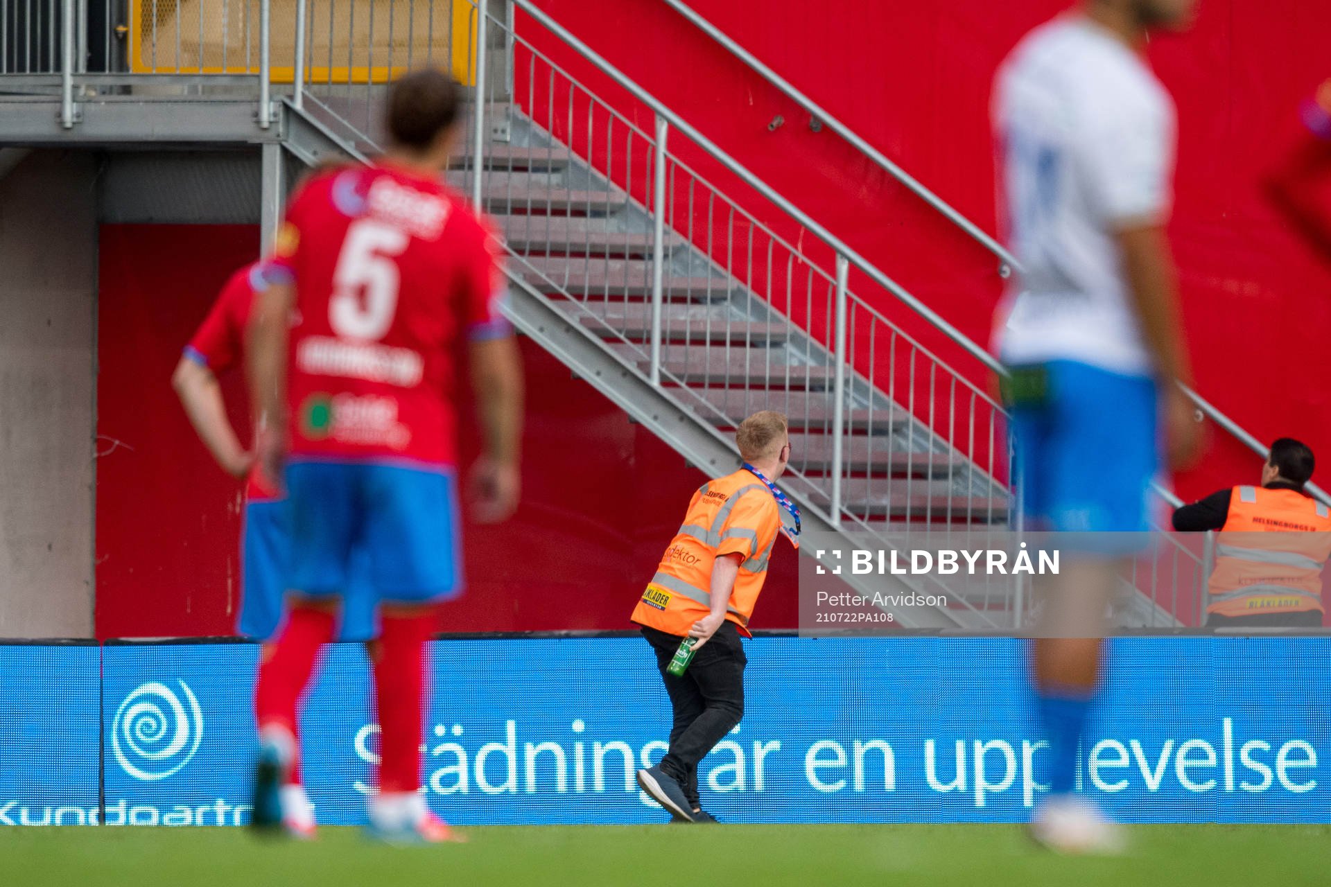 En publikvärd plockar bort en inkastad flaska