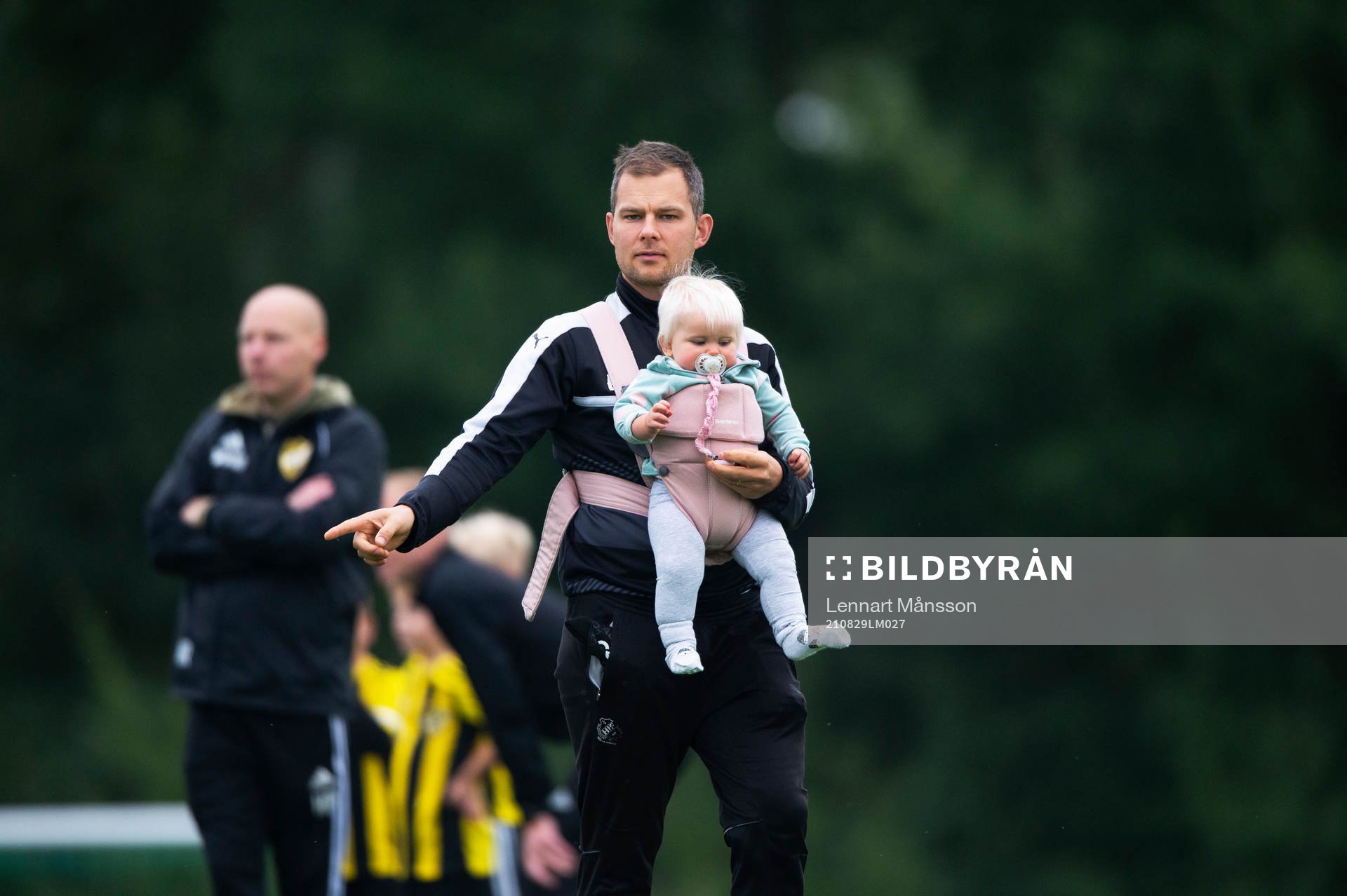 Pappa med bebis i sele coachar sitt lag i matchen för