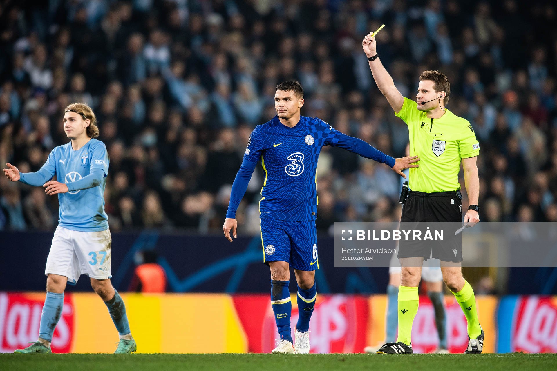 Referee Felix Brych shows Thiago Silva of Chelsea a yellow