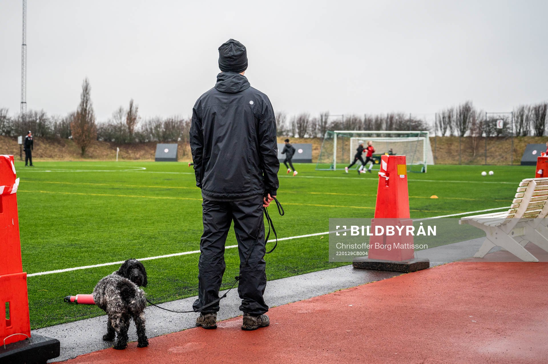 En förälder står och tittar ut över träningsplanen