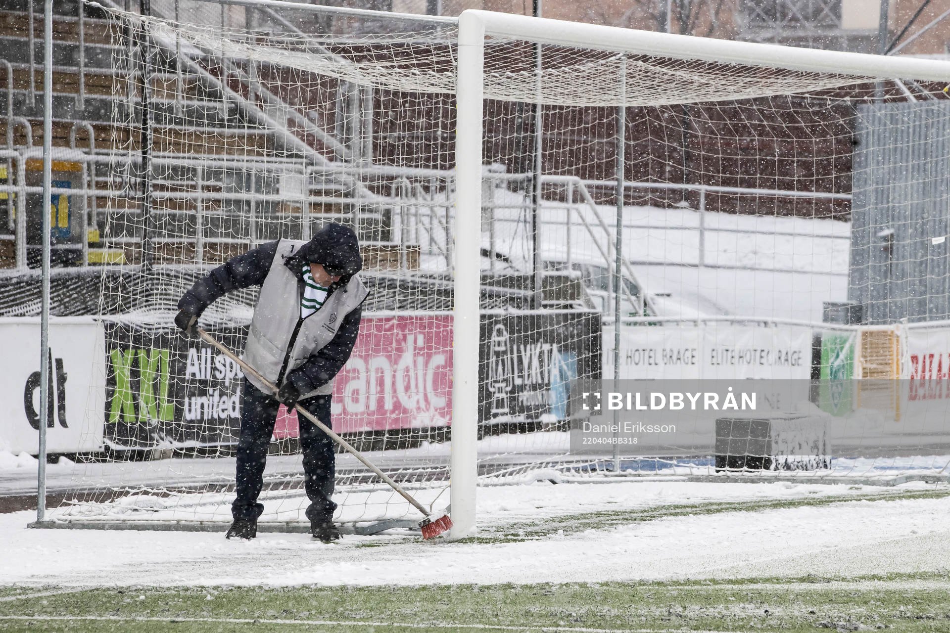 Funktionärer sopar av planen innan fotbollsmatchen i