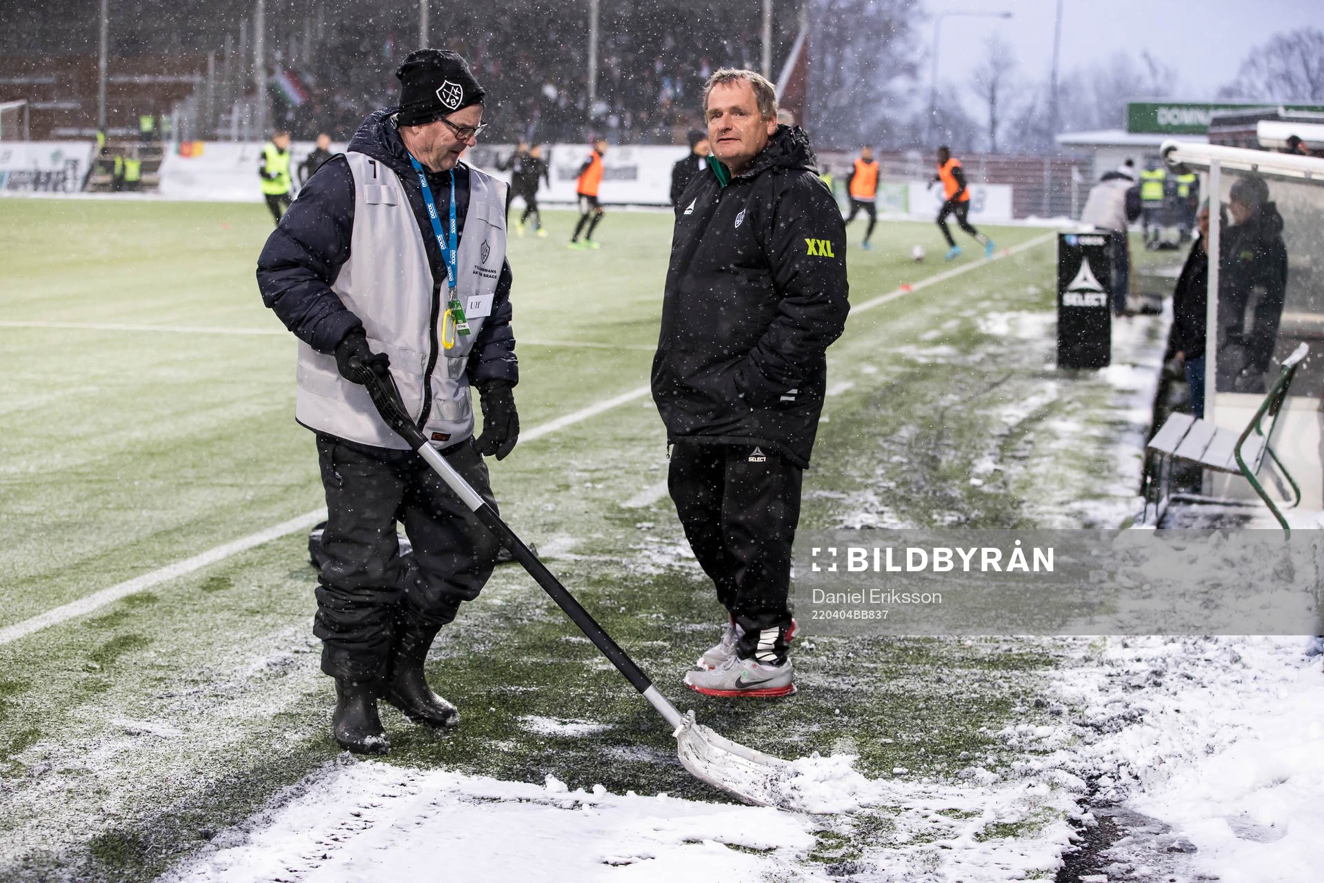 Funktionärer skottar snö innan fotbollsmatchen i