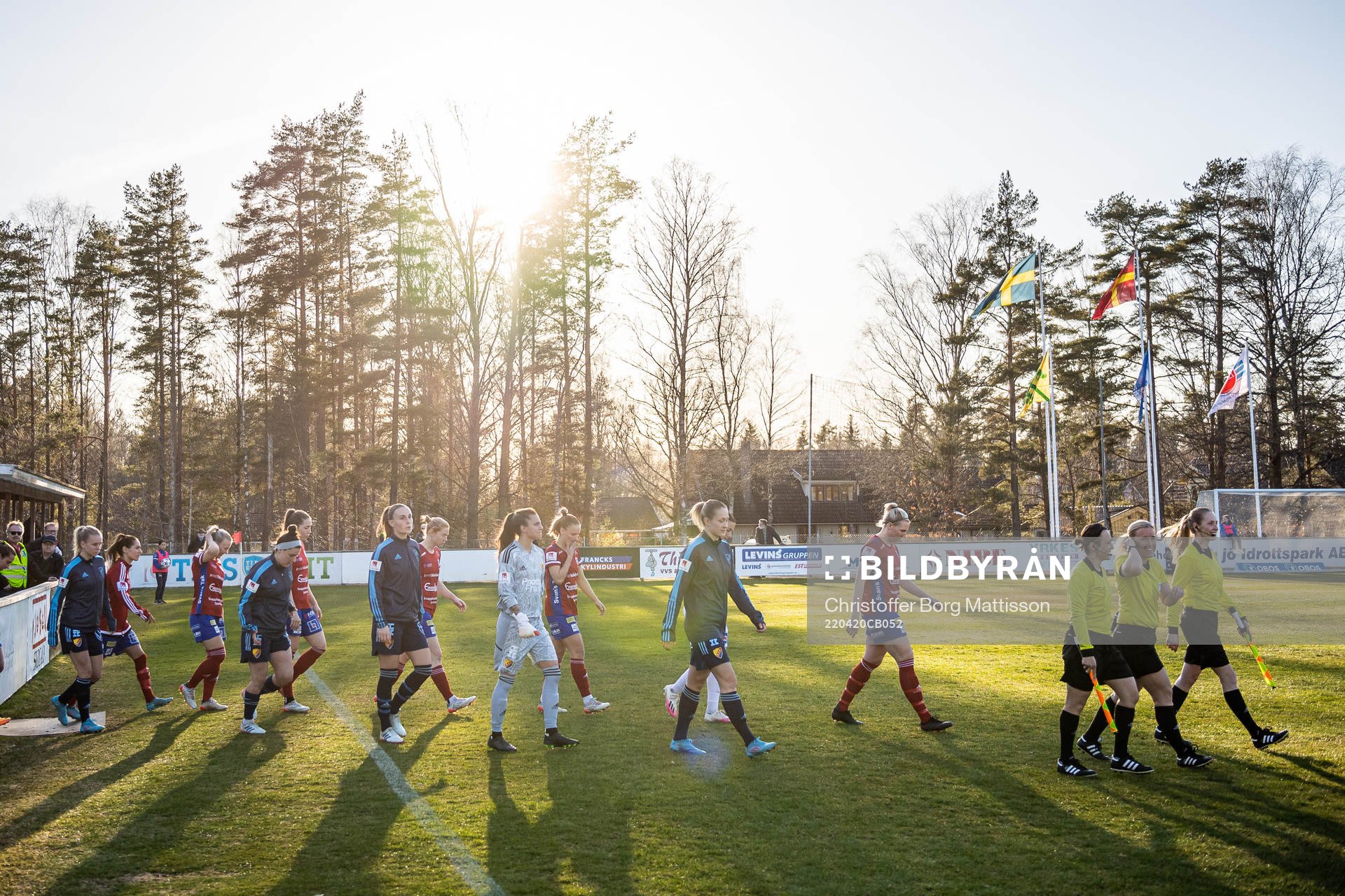 Båda lagens spelare gör entré till fotbollsmatchen i