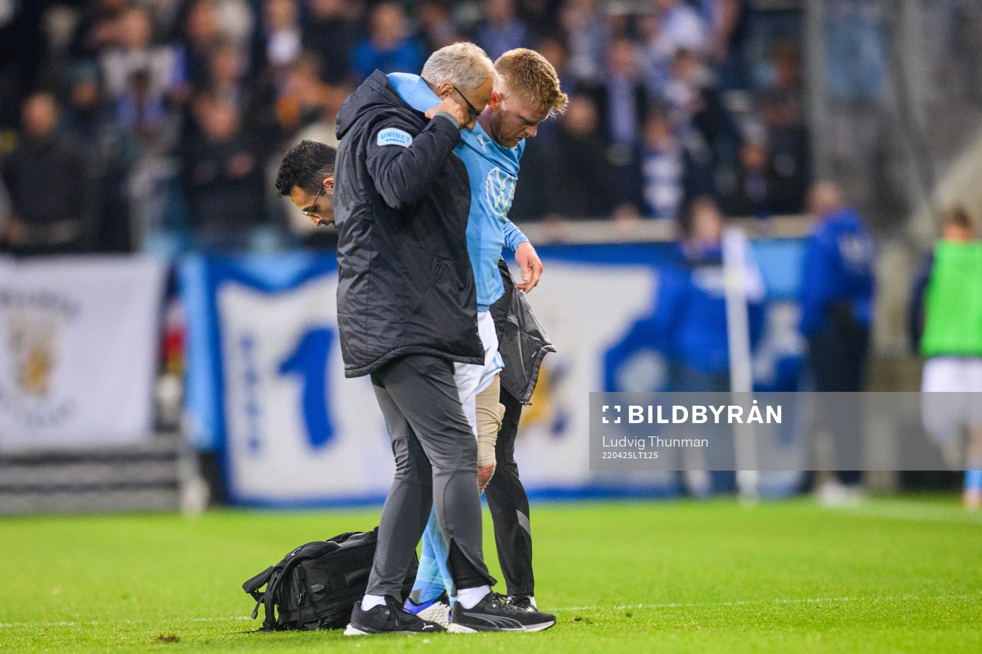 Malmö FFs Anders Christiansen leds av plan med hjälp av läkare Pär Herbertsson under fotbollsmatchen i Allsvenskan mellan Malmö FF och IFK Göteborg den 25 april 2022 i Malmö.