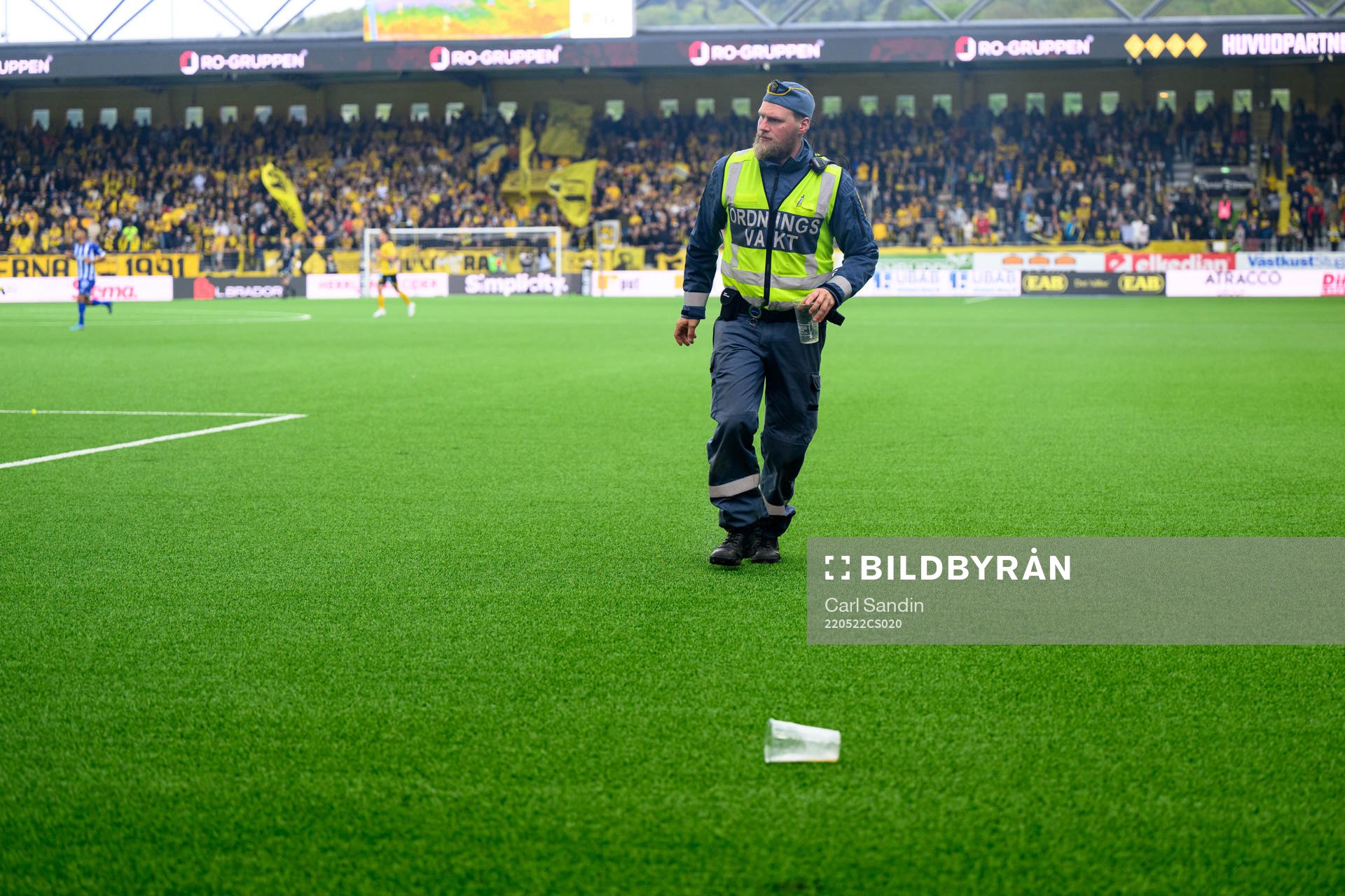 En ordningsvakt plockar upp inkastade föremål från planen