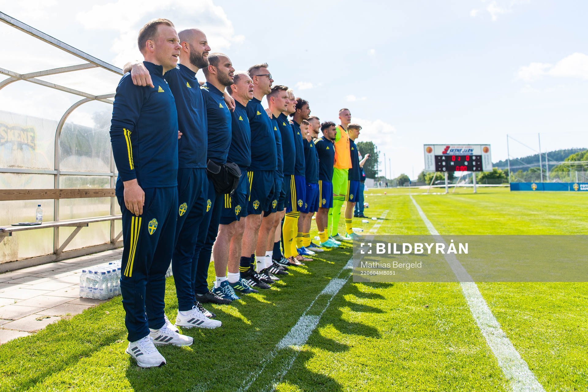 Sveriges förbundskapten Viktor Eriksson och assisterande förbundskapten Johan Palm under nationalsången inför fotbollsmatchen i trenationersturneringen för P18 mellan Sverige och Finland den 4 juni 2022 i Skene. 