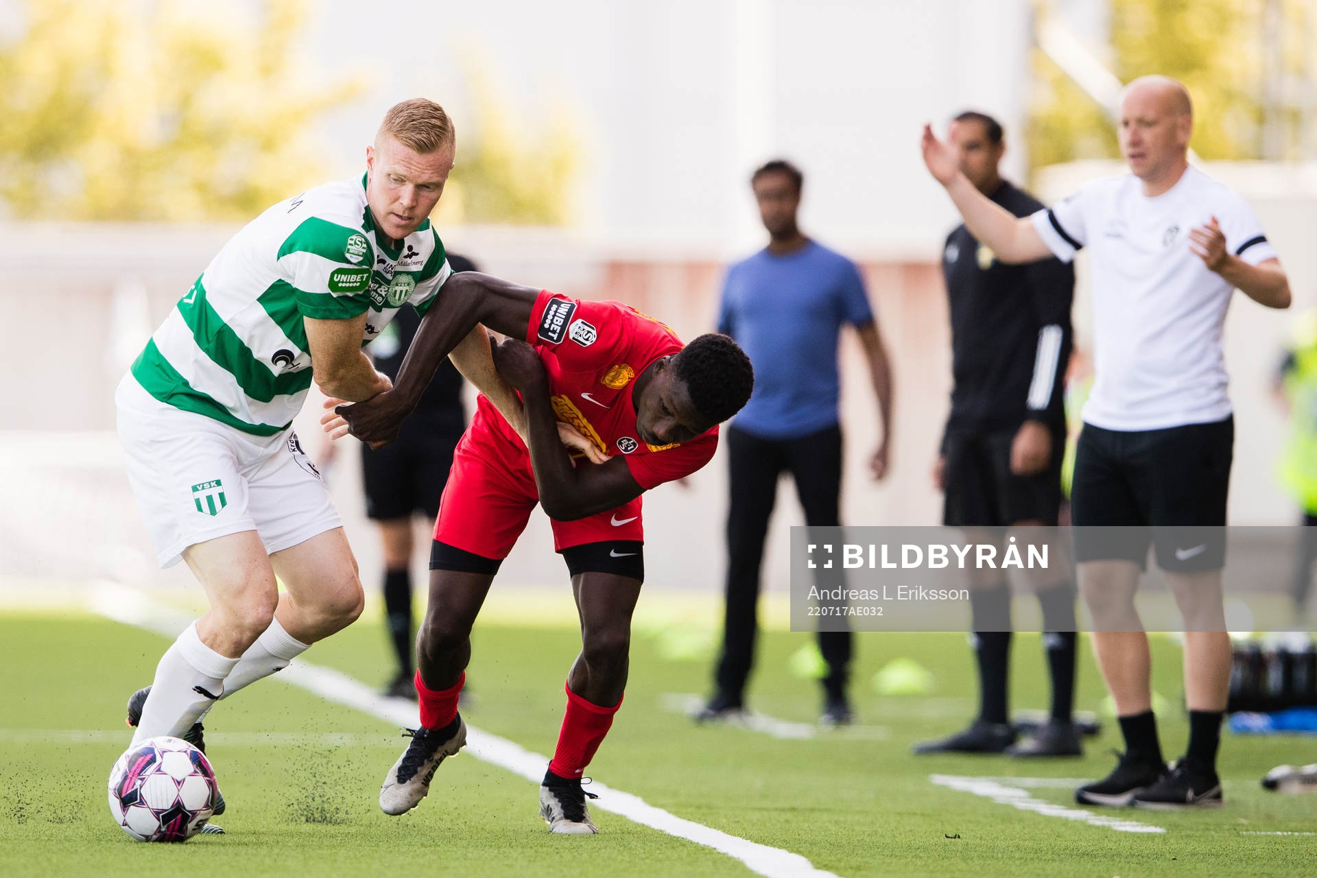 Västerås David Engström och Landskronas Ousmane Diawara i en duell framför Landskronas tränare Billy Magnusson under fotbollsmatchen i Superettan mellan Västerås SK och Landskrona den 17 juli 2022 i Västerås.