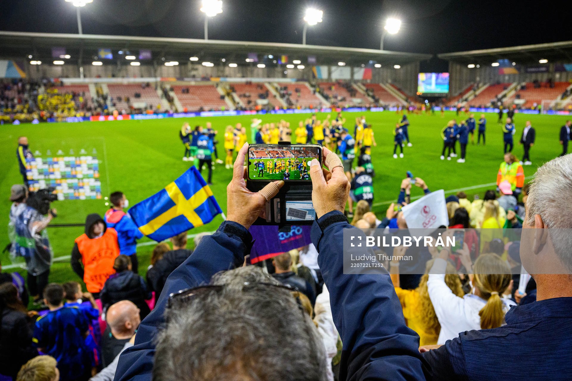A spectator takes a photo of players of Sweden celebrating