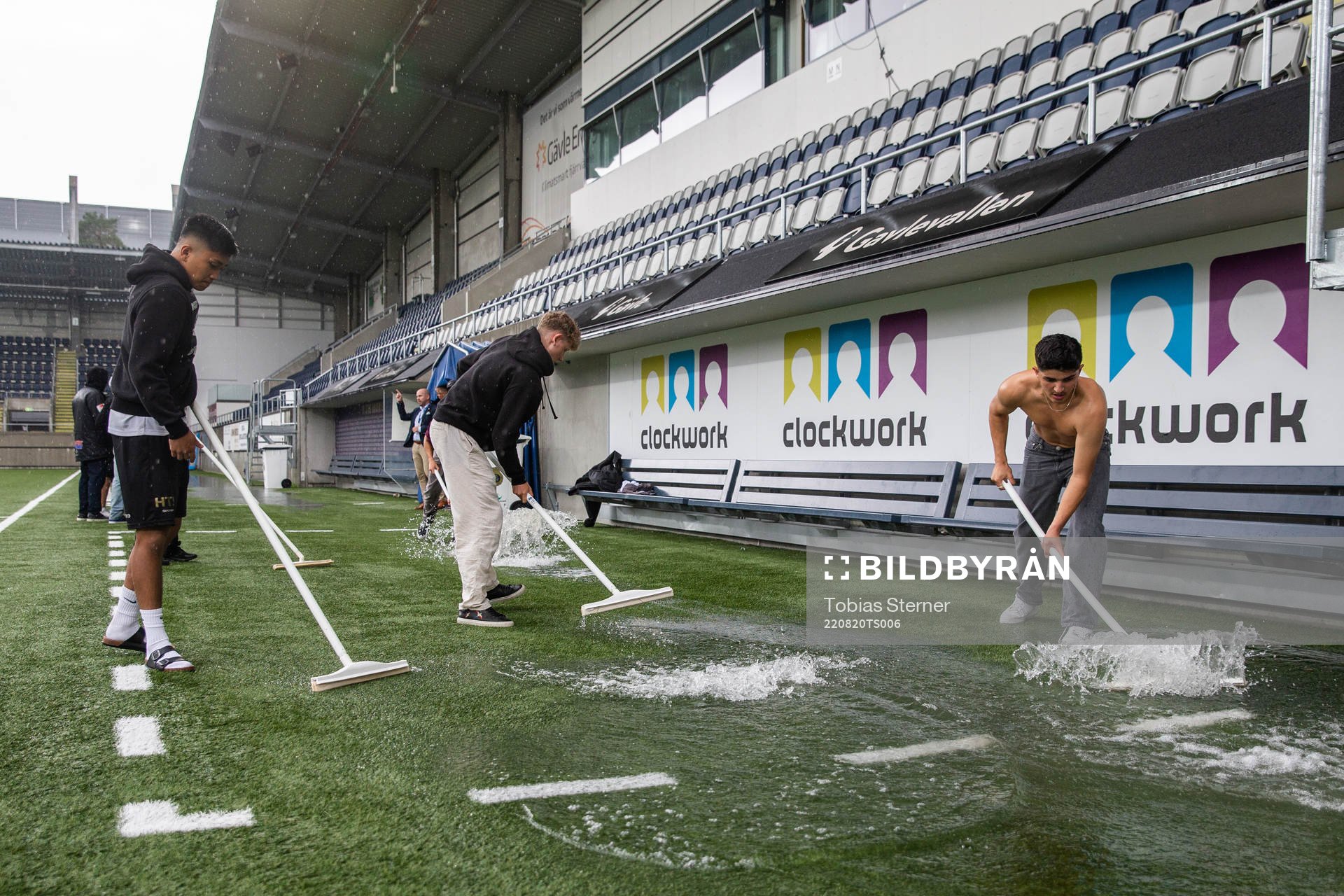Funktionärer skrapar bort vatten från planen