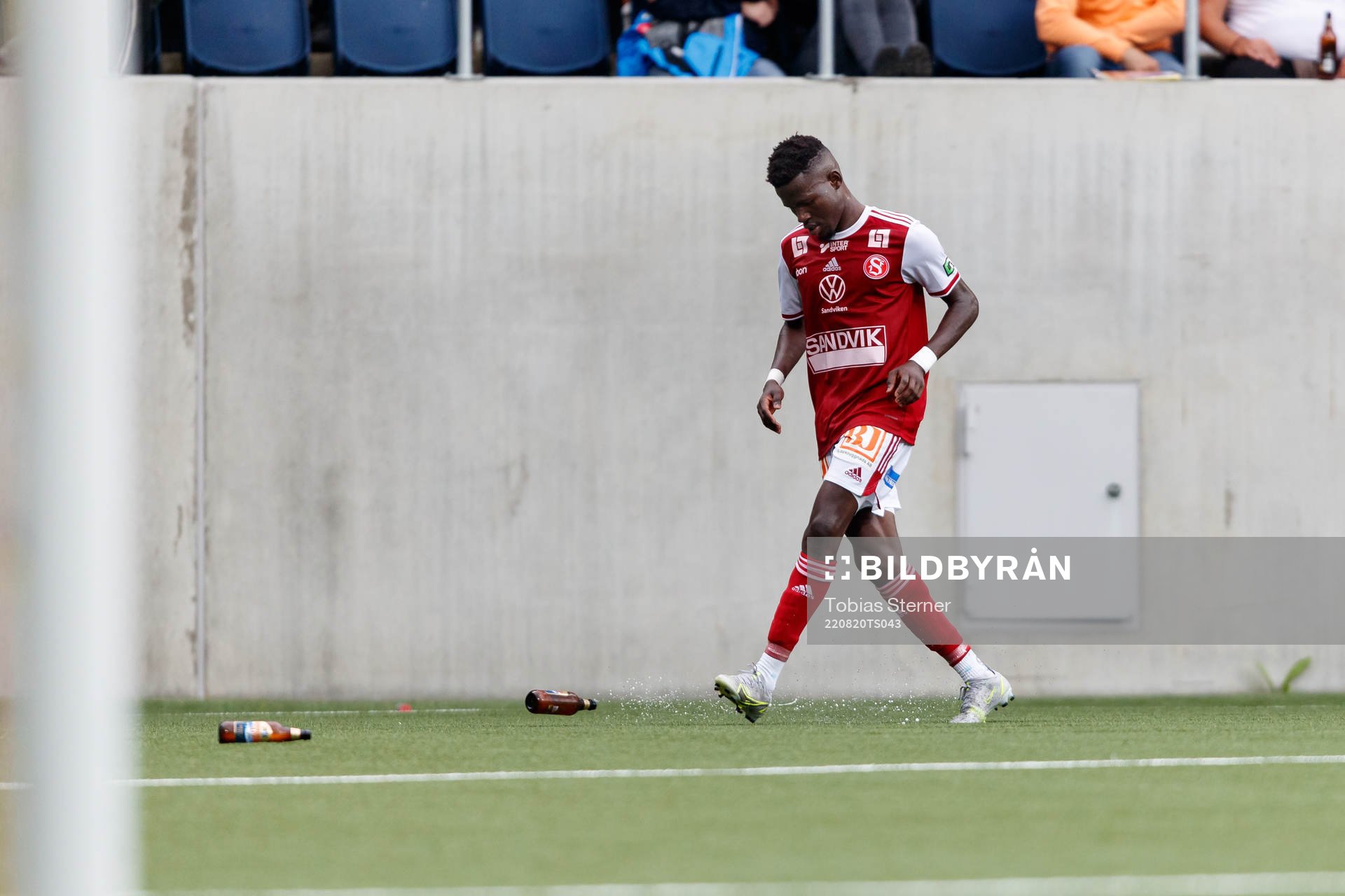 Sandvikens Mamadou Kouyate sparkar undan ölflaskor under fotbollsmatchen i Ettan norra mellan Gefle och Sandviken den 20 augusti 2022 i Gävle.