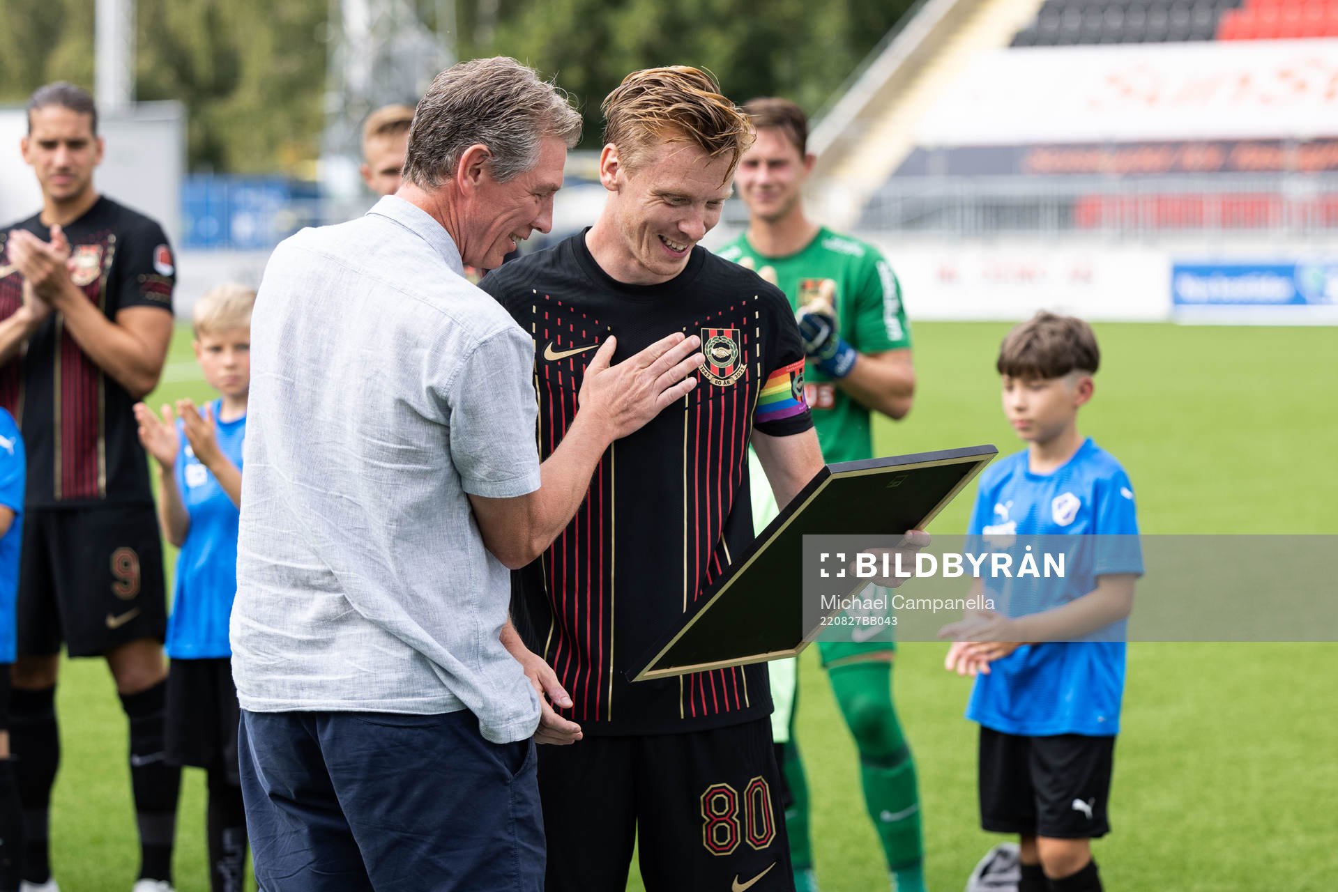 Berndt Magnusson ger en tavla till sin son Gustav Sandberg Magnusson för flest matcher genom tiderna för Brommapojkarna inför fotbollsmatchen i Superettan mellan Brommapojkarna och Halmstad den 27 augusti 2022 i Stockholm.