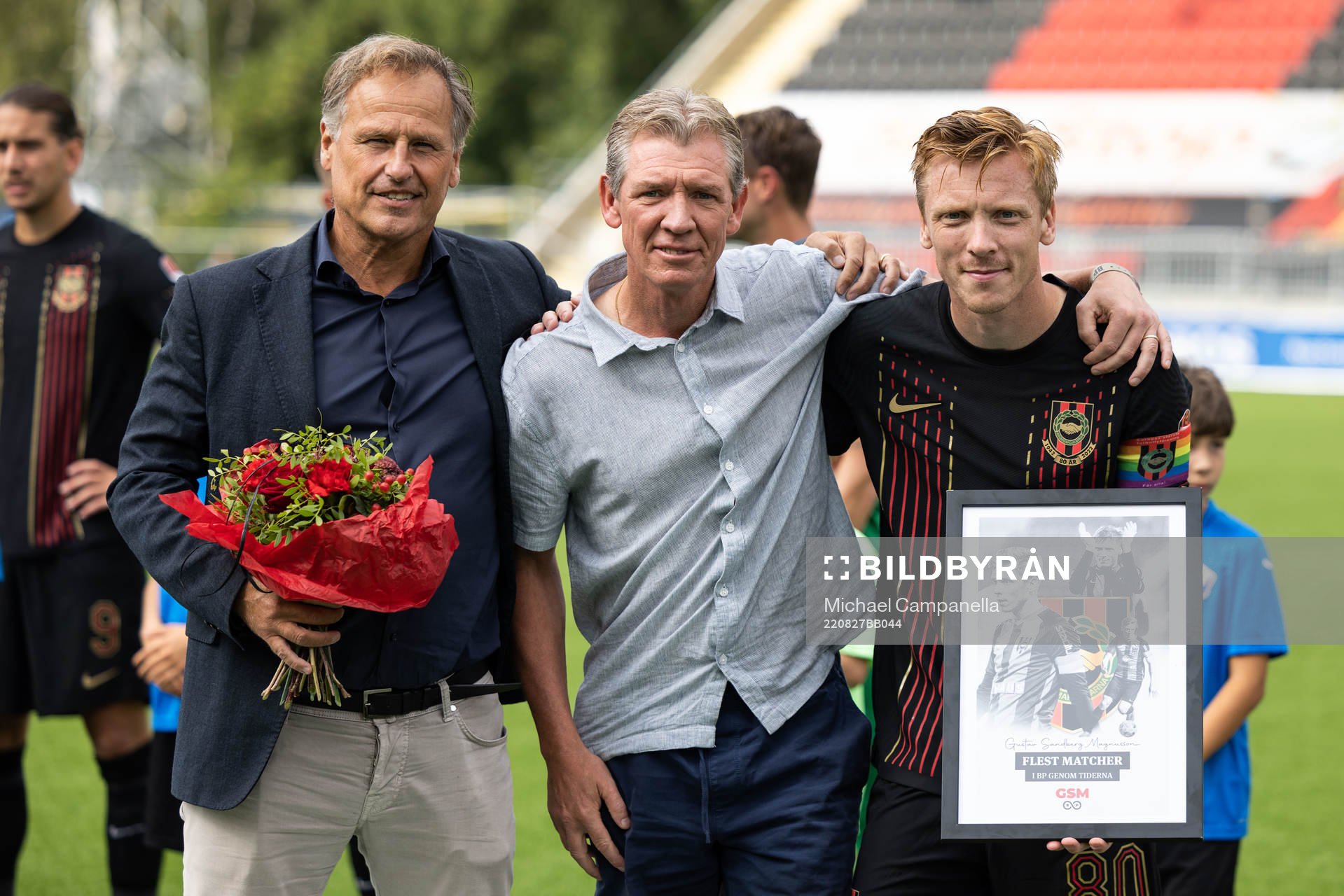 Brommapojkarnas ordförande Manfred Aronsson och Berndt Magnusson ger en tavla till Gustav Sandberg Magnusson för flest matcher genom tiderna för Brommapojkarna inför fotbollsmatchen i Superettan mellan Brommapojkarna och Halmstad den 27 augusti 2022 i Stockholm.