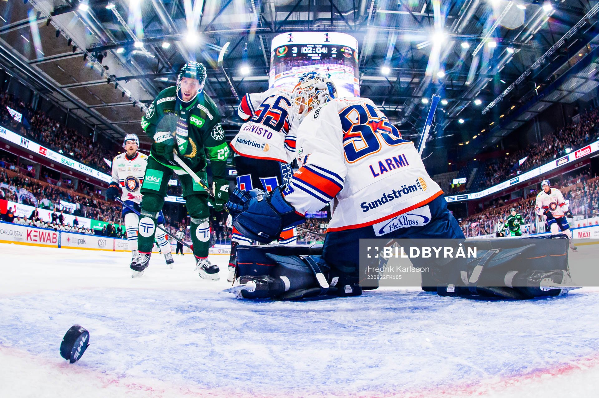 En puck bakom Växjös målvakt Emil Larmi och Färjestads