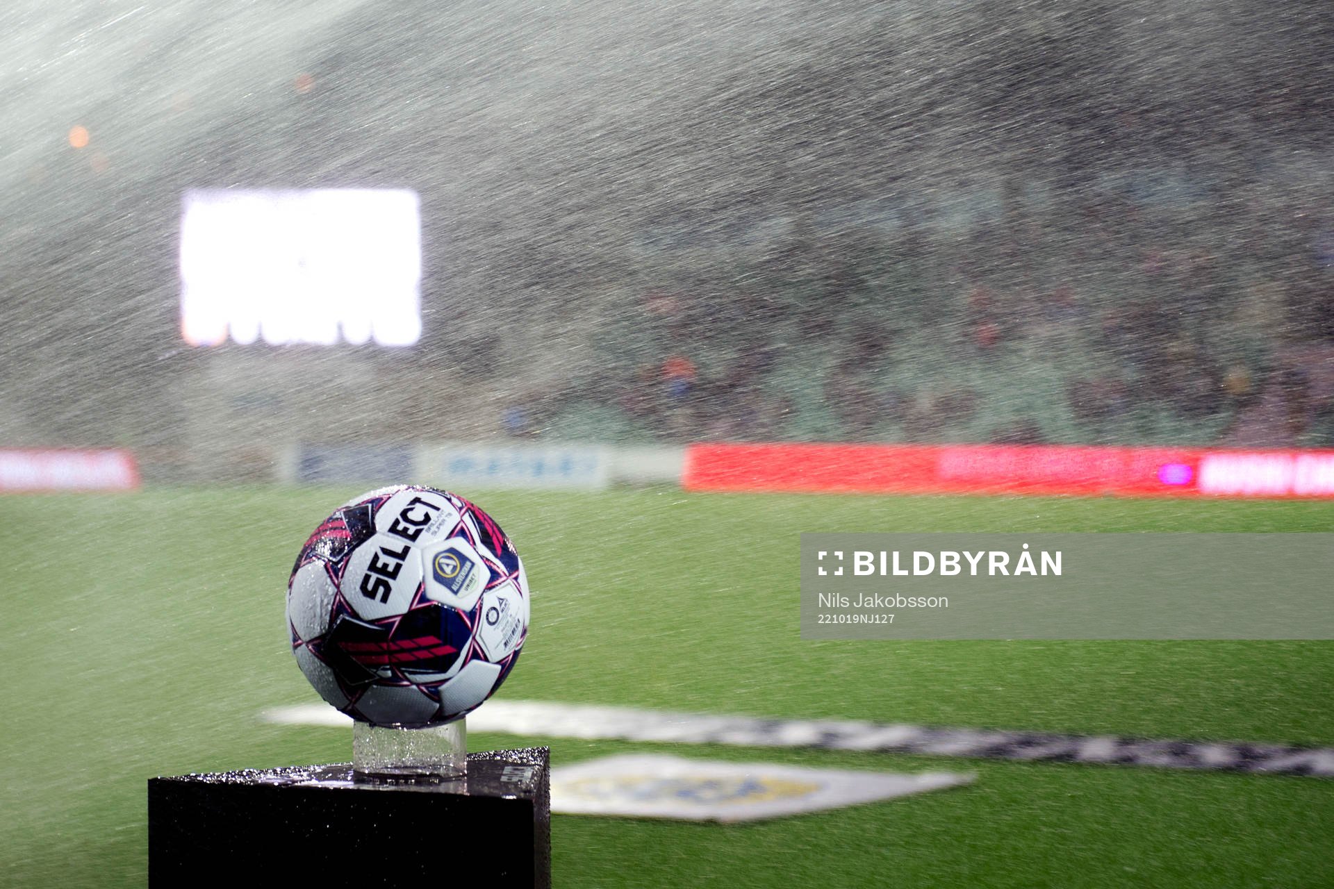 En boll blir blöt av bevattning innan fotbollsmatchen i