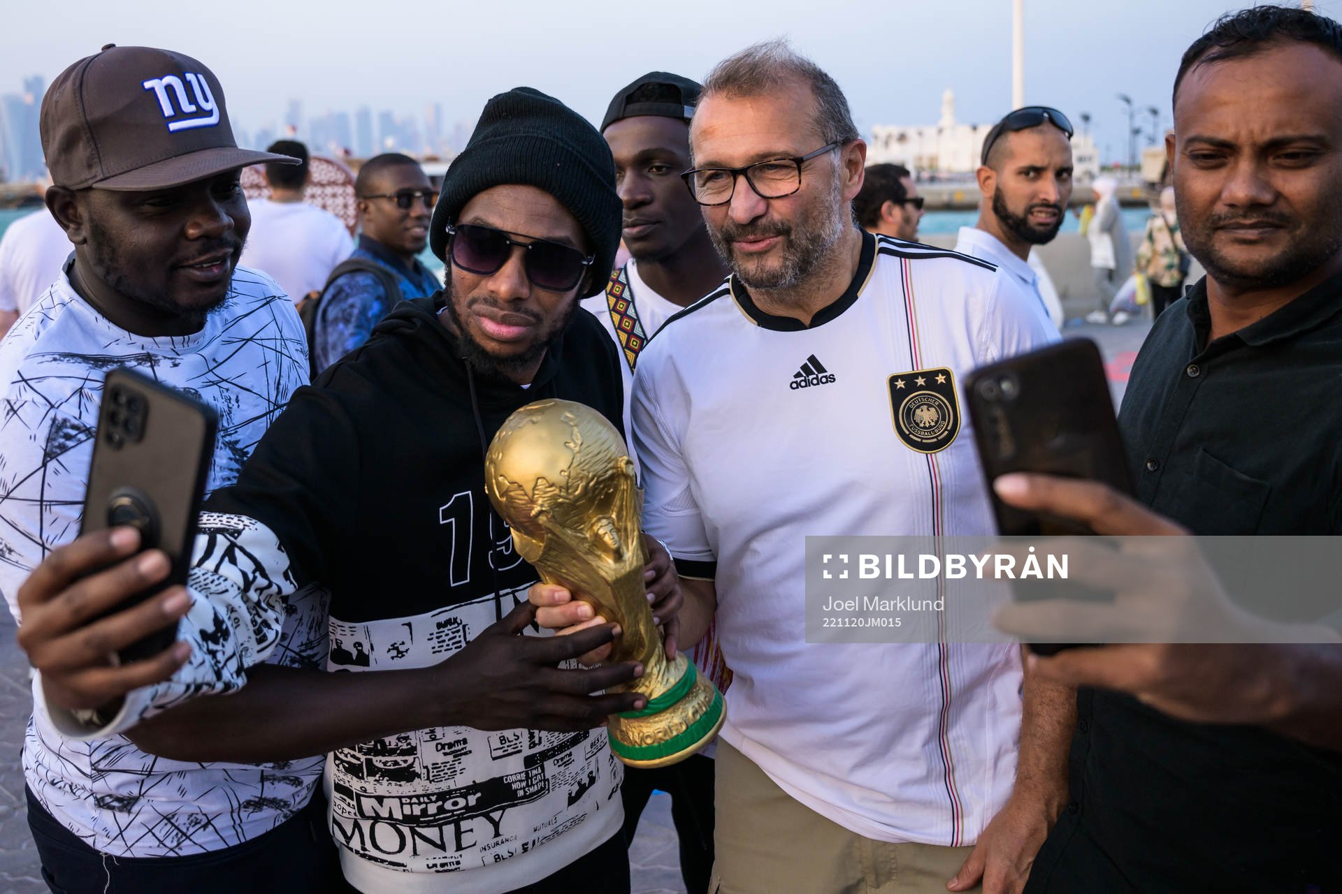 People pose with a trophy replica at the Corniche Promenade