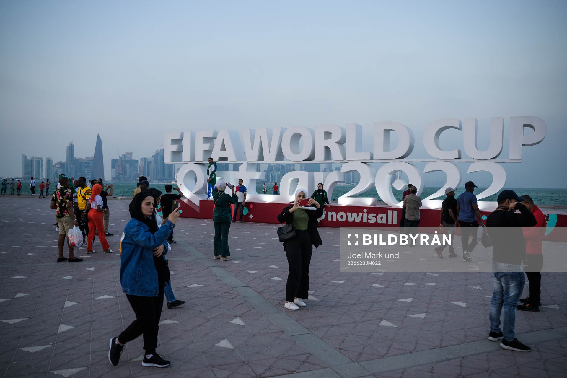People pose in front of a World Cup logo at Corniche