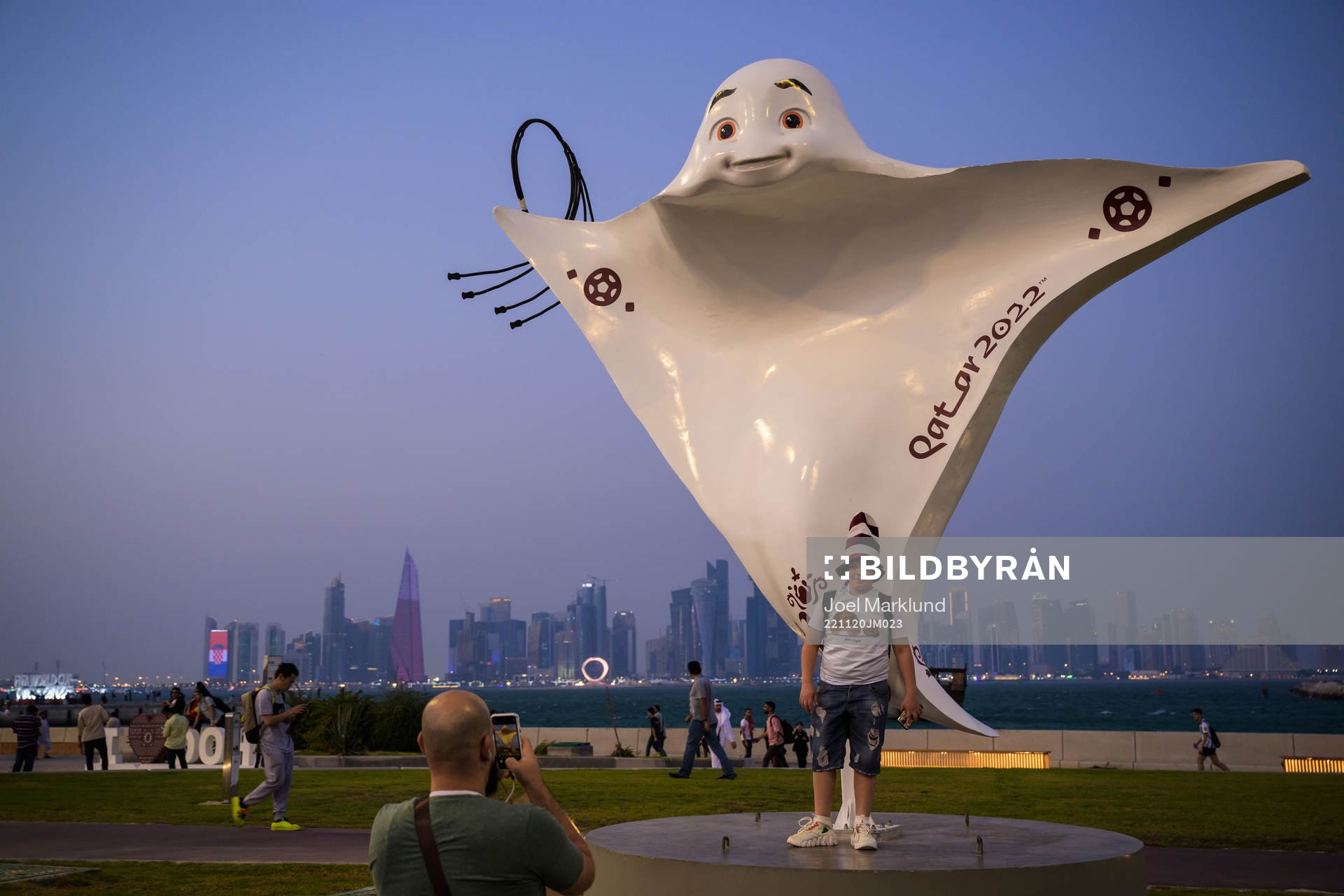 A boy poses in front of the mascot La'eeb