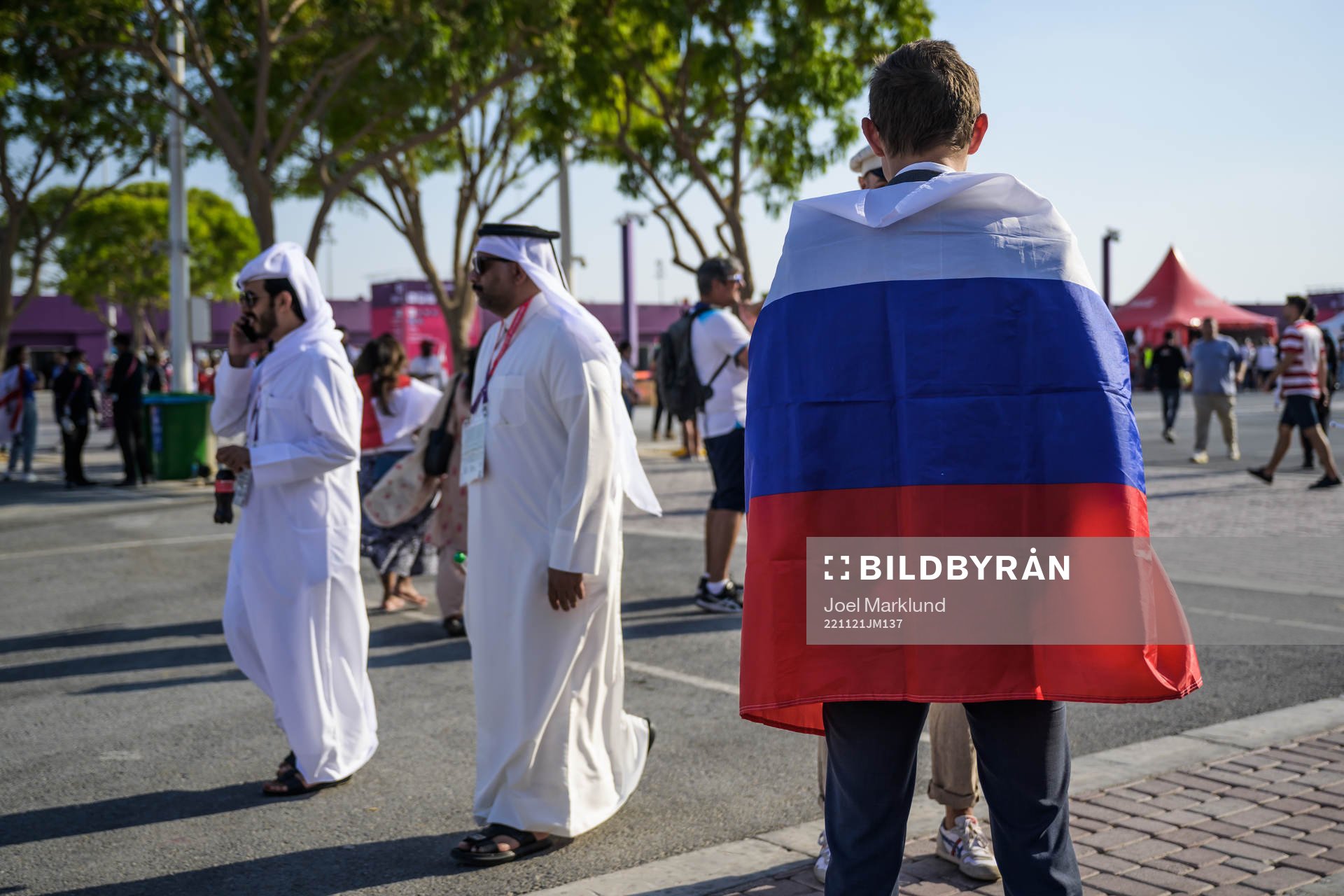Men in traditional Qatari clothing pass by a man wearing a