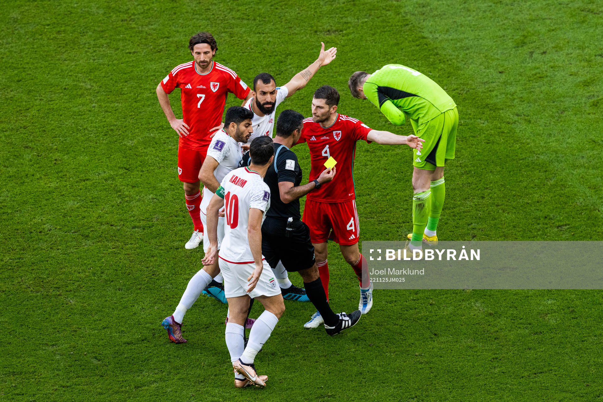 Karim Ansarifard of Iran with Joe Allen and Ben Davies of Wales as they react towards the referee as goalkeeper Wayne Hennessey receives a yellow card (that is changed to a red after VAR review) the referee during the FIFA World Cup 2022 football match between Wales and Iran on November 25, 2022 in Doha.