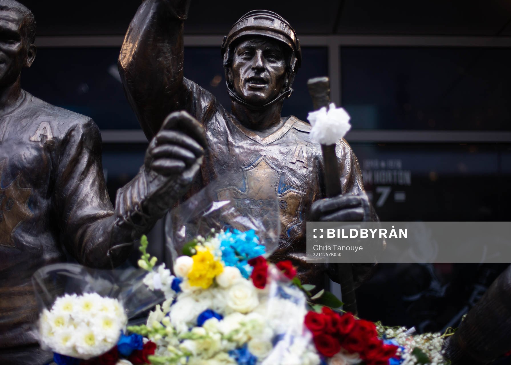 Flowers are shown in memorial at a statue of the late