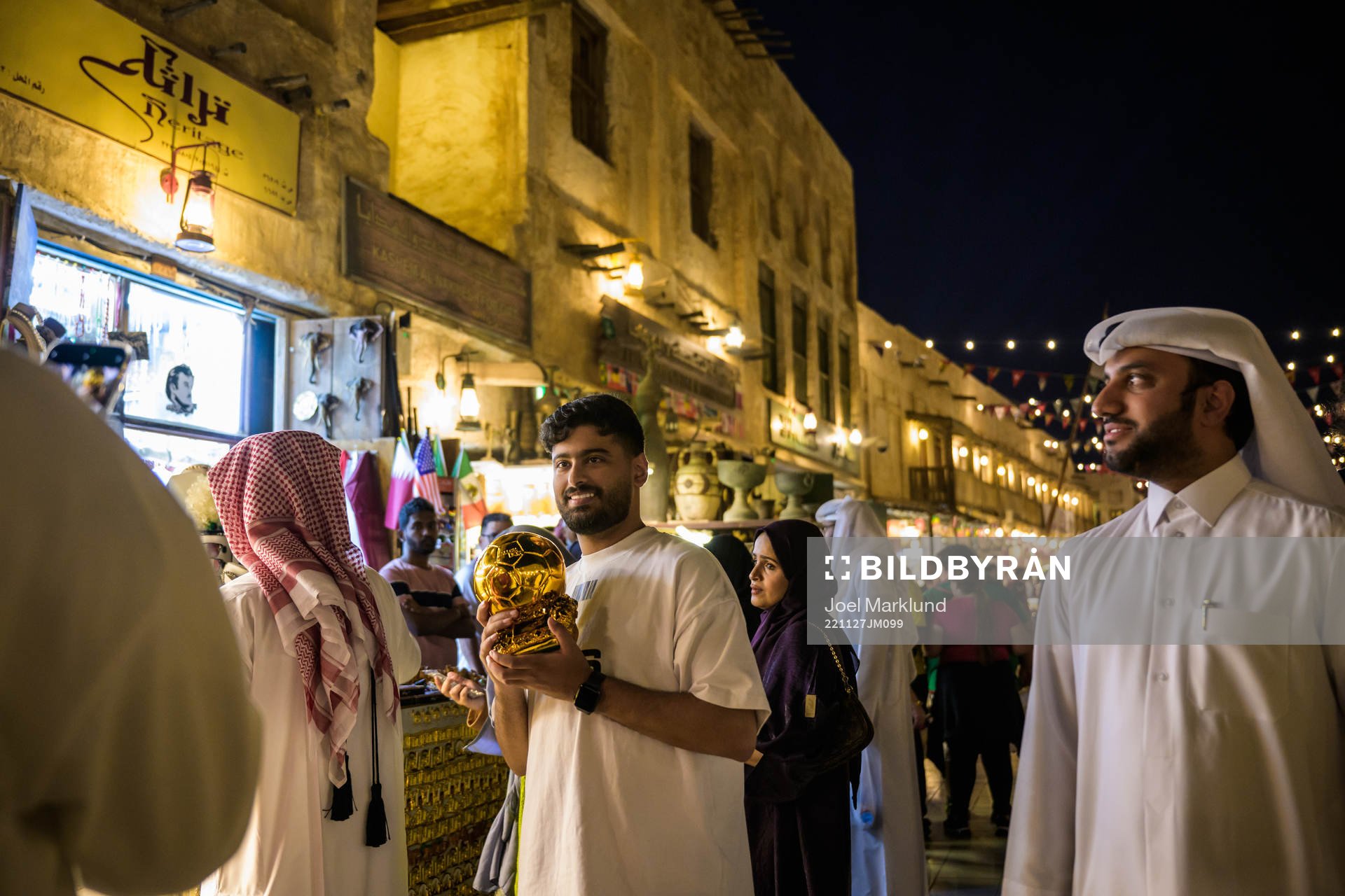 A man holds a golden football outside a store