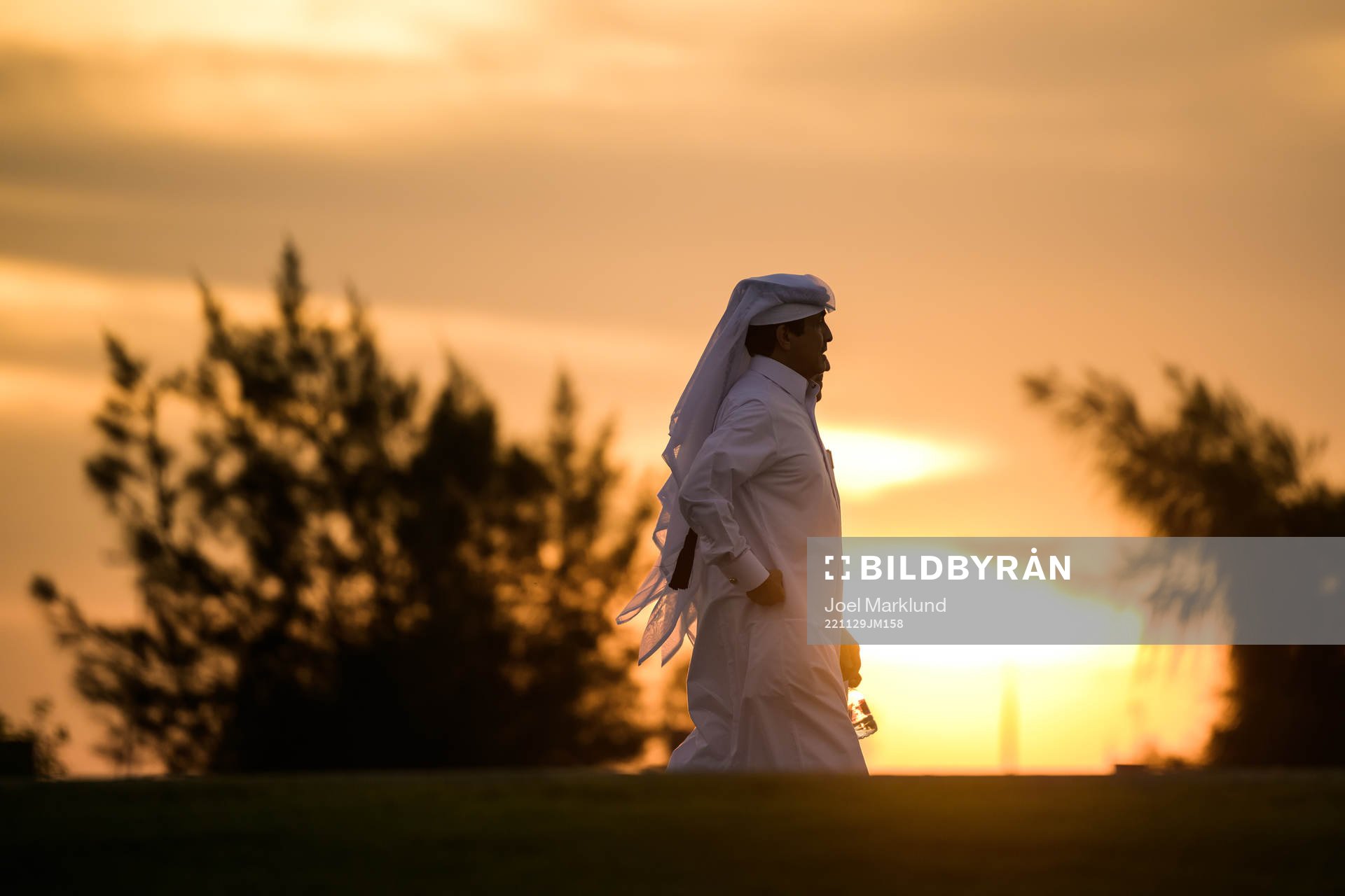 Men in Qatari clothing walk towards the arena