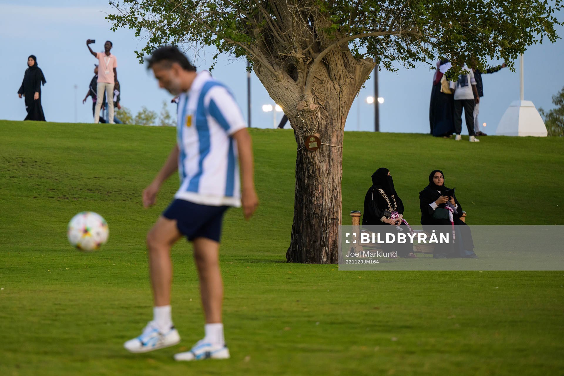 Two Qatari women see a man playing football