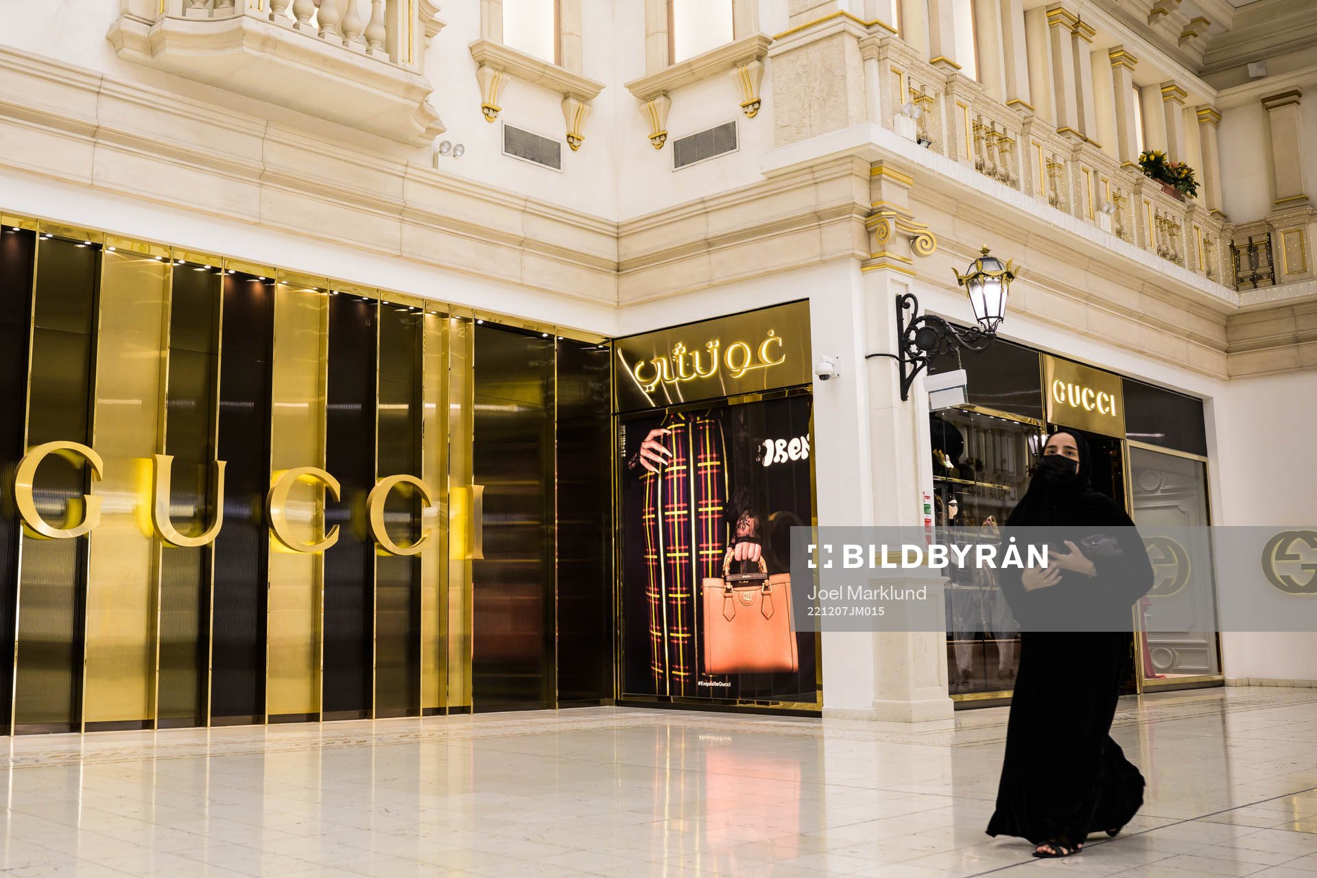A woman walks past a Gucci store at Villaggio Mall