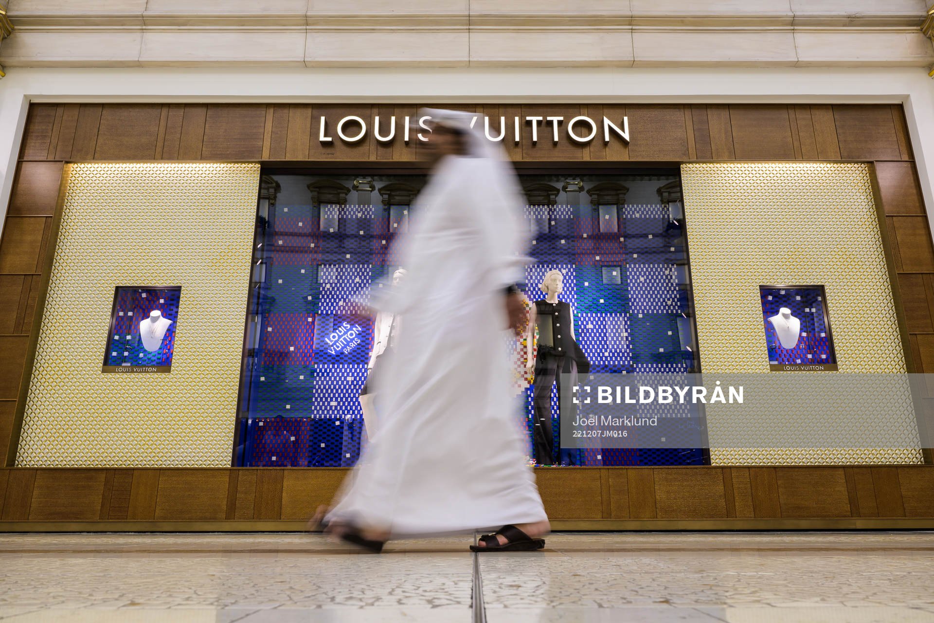 A man walks past a Louis Vuitton store at Villaggio Mall