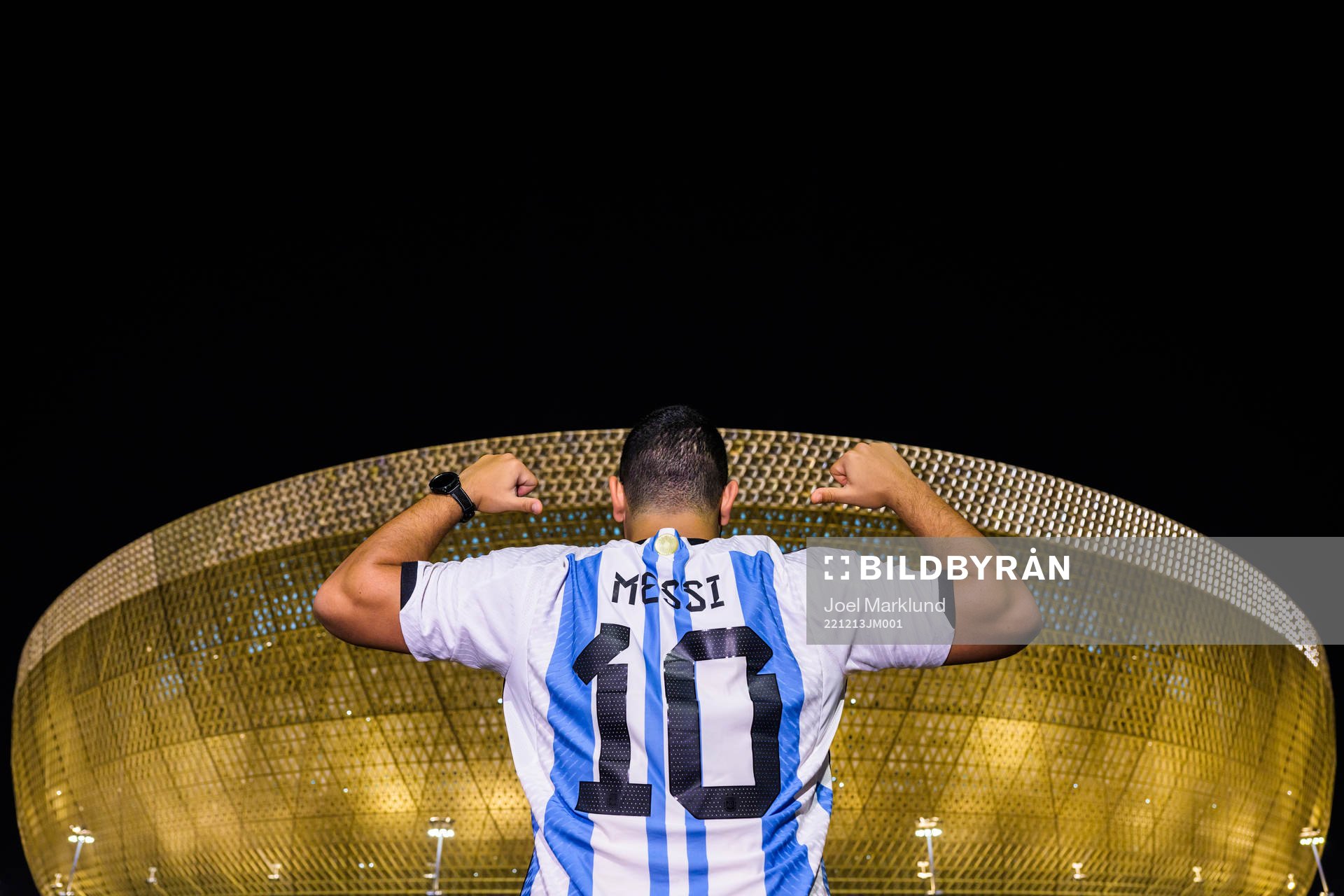 A man with a Lionel Messi jersey poses in front of Lusail