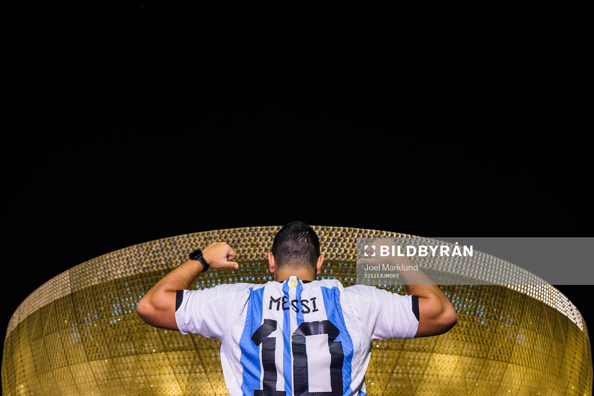A man with a Lionel Messi jersey poses in front of Lusail