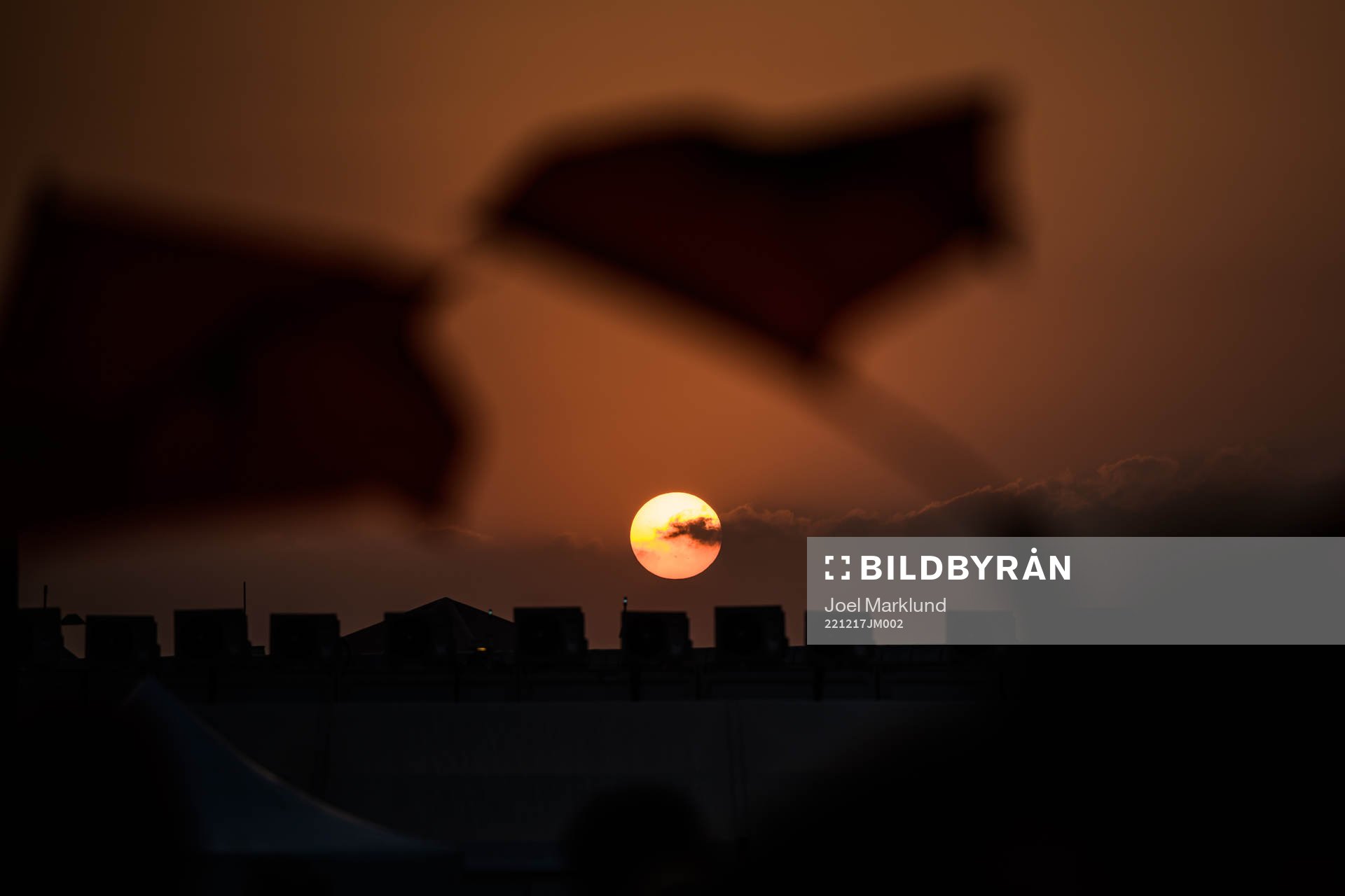 People wave Moroccan flags at sunset