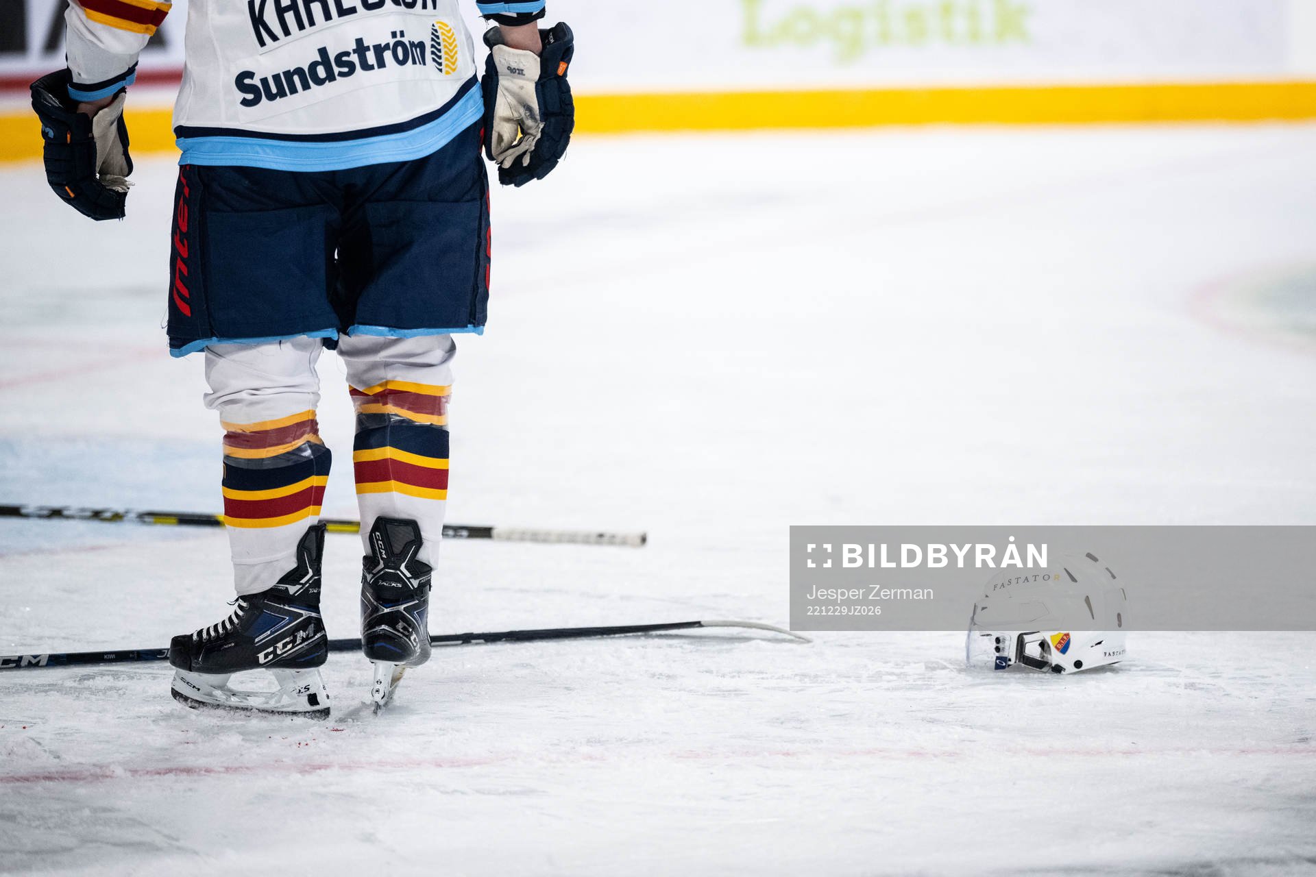 Hockeyhjälm och klubbor på isen
