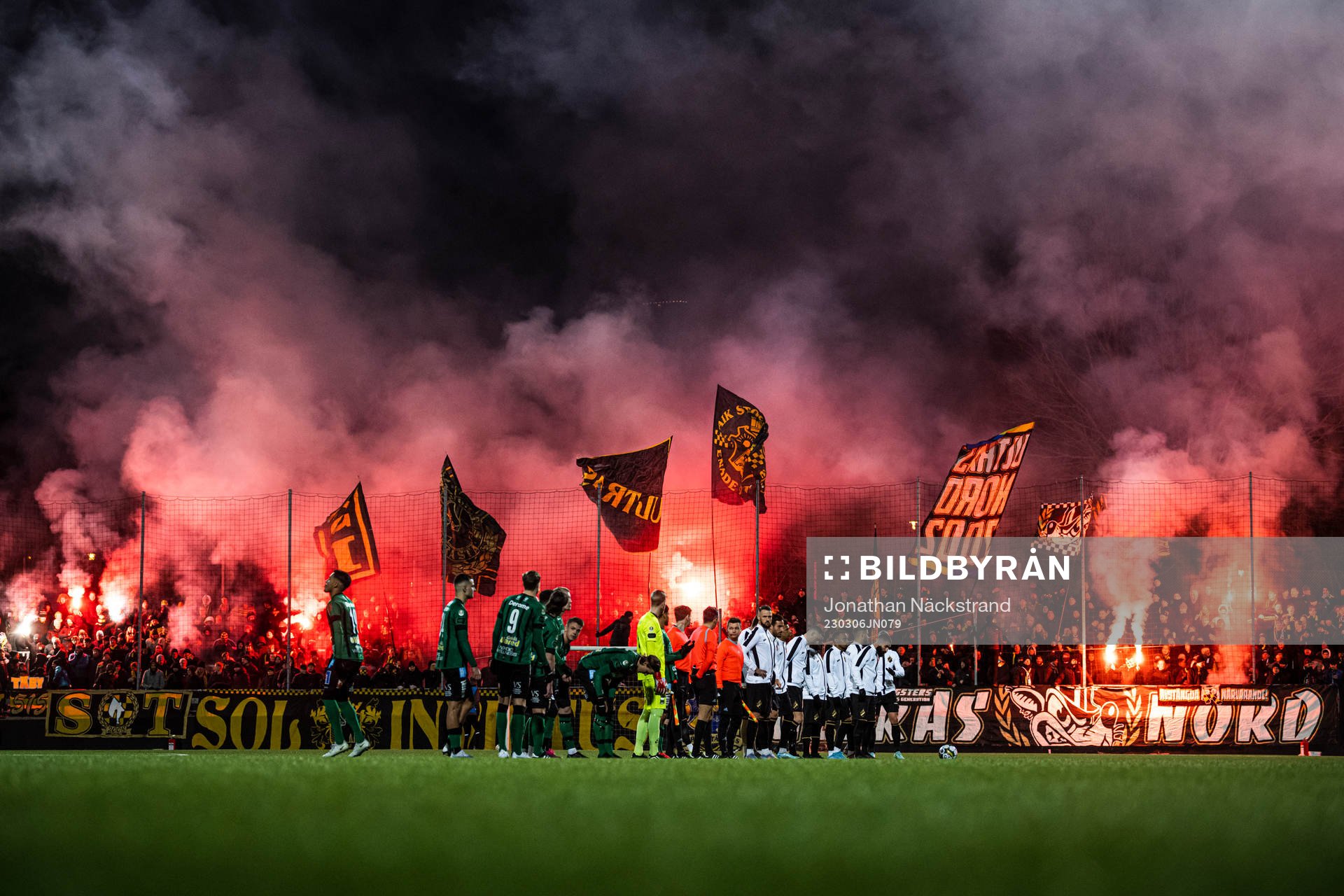 Varbergs och AIKs spelare framför supportar med bengaliska