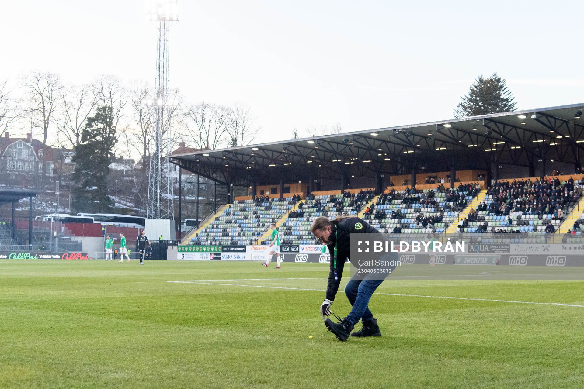 En funktionär plockar skärp från planen