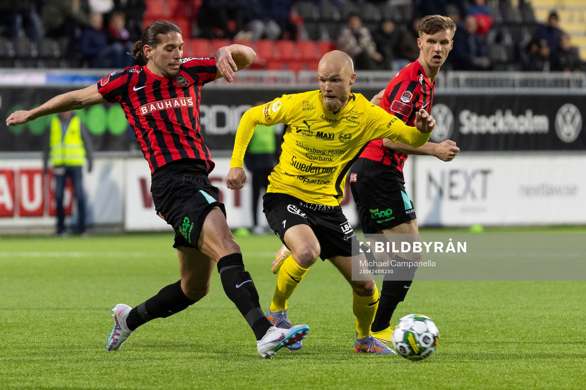 Brommapojkarnas Nikola Vasic och Samuel Leach Holm mot Mjällbys Viktor Gustafson under fotbollsmatchen i Allsvenskan mellan Brommapojkarna och Mjällby den 24 april 2023 i Stockholm.
