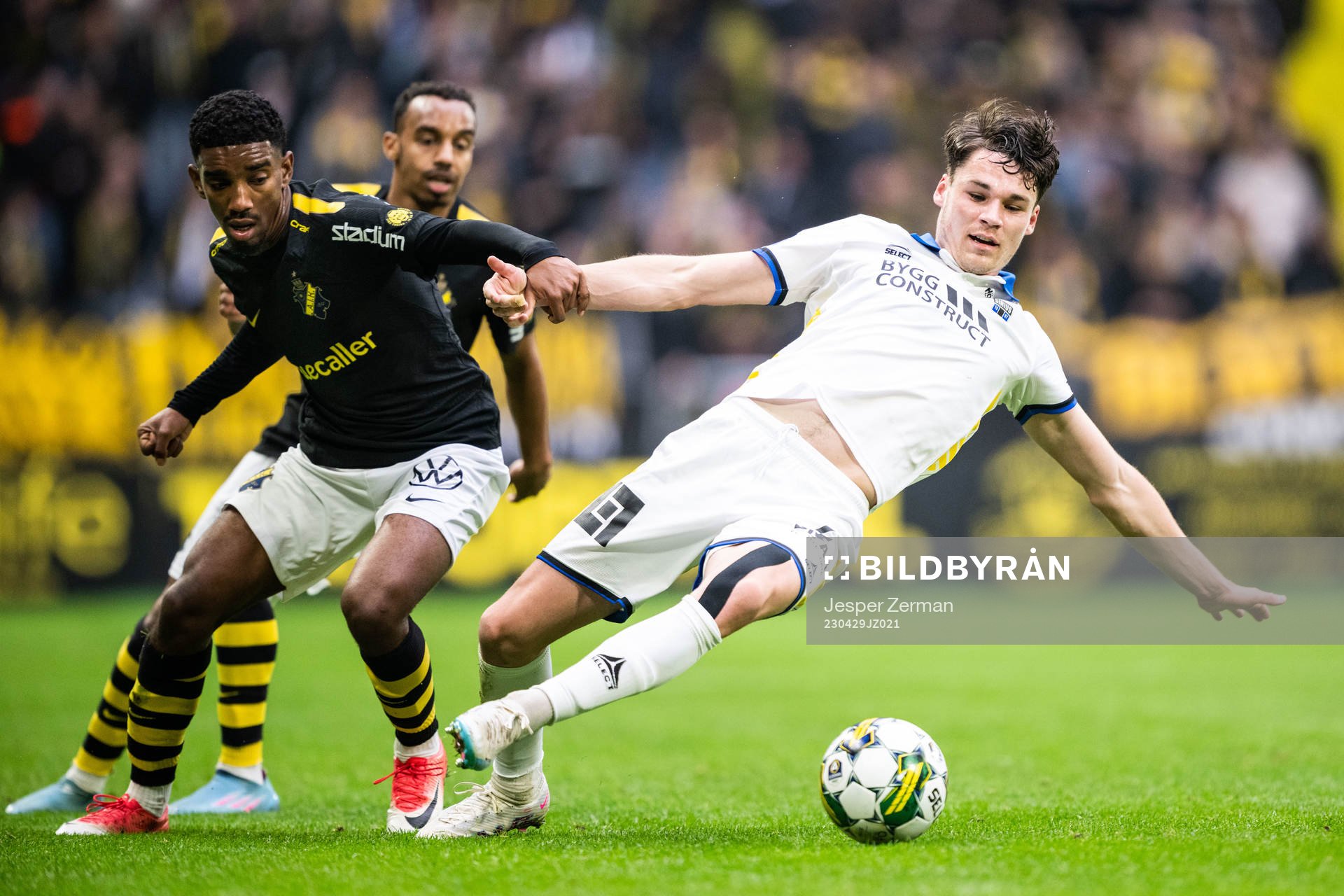 AIKs Alexander Fesshaie Beraki och Bilal Hussein mot Sirius Jamie Roche under fotbollsmatchen i Allsvenskan mellan AIK och Sirius den 29 april 2023 i Stockholm.